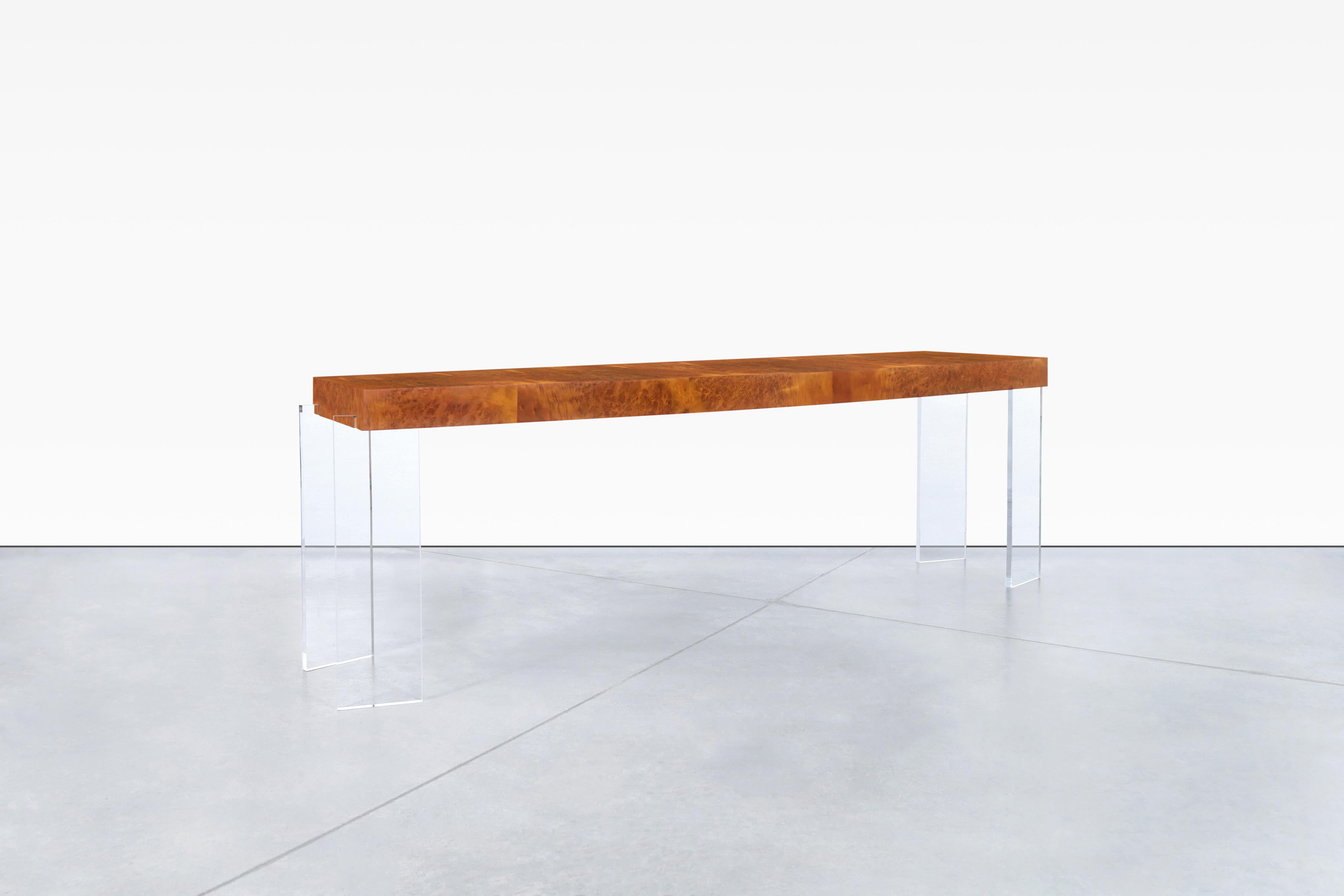 This stunning vintage console table is a true work of art. Crafted from beautifully grained burl wood and featuring sleek angled lucite legs, it exudes a sense of understated elegance. Measuring 8ft long, this piece is generously sized and offers