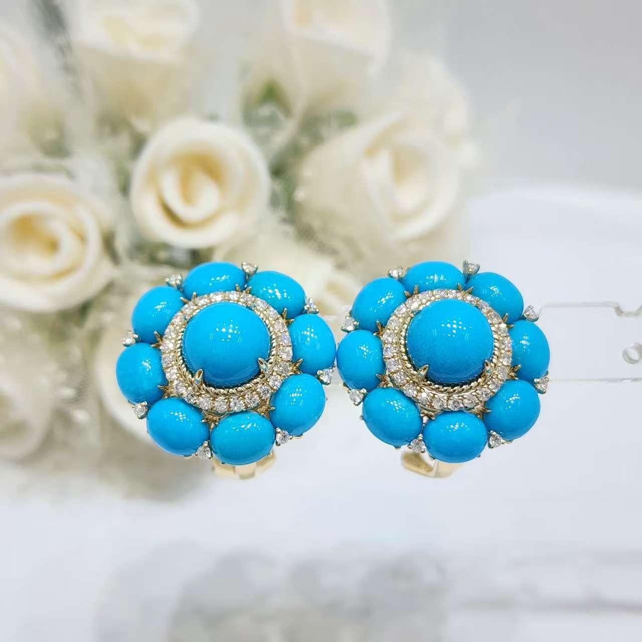 Diese exquisiten Ohrringe sind aus 14-karätigem Gelbgold gefertigt und zeigen eine harmonische Mischung aus lebhaftem Türkis und funkelnden Diamanten. In der Mitte jedes Ohrrings liegt ein 8 mm großer Türkis-Cabochon, der von sechzehn 5x6 mm großen