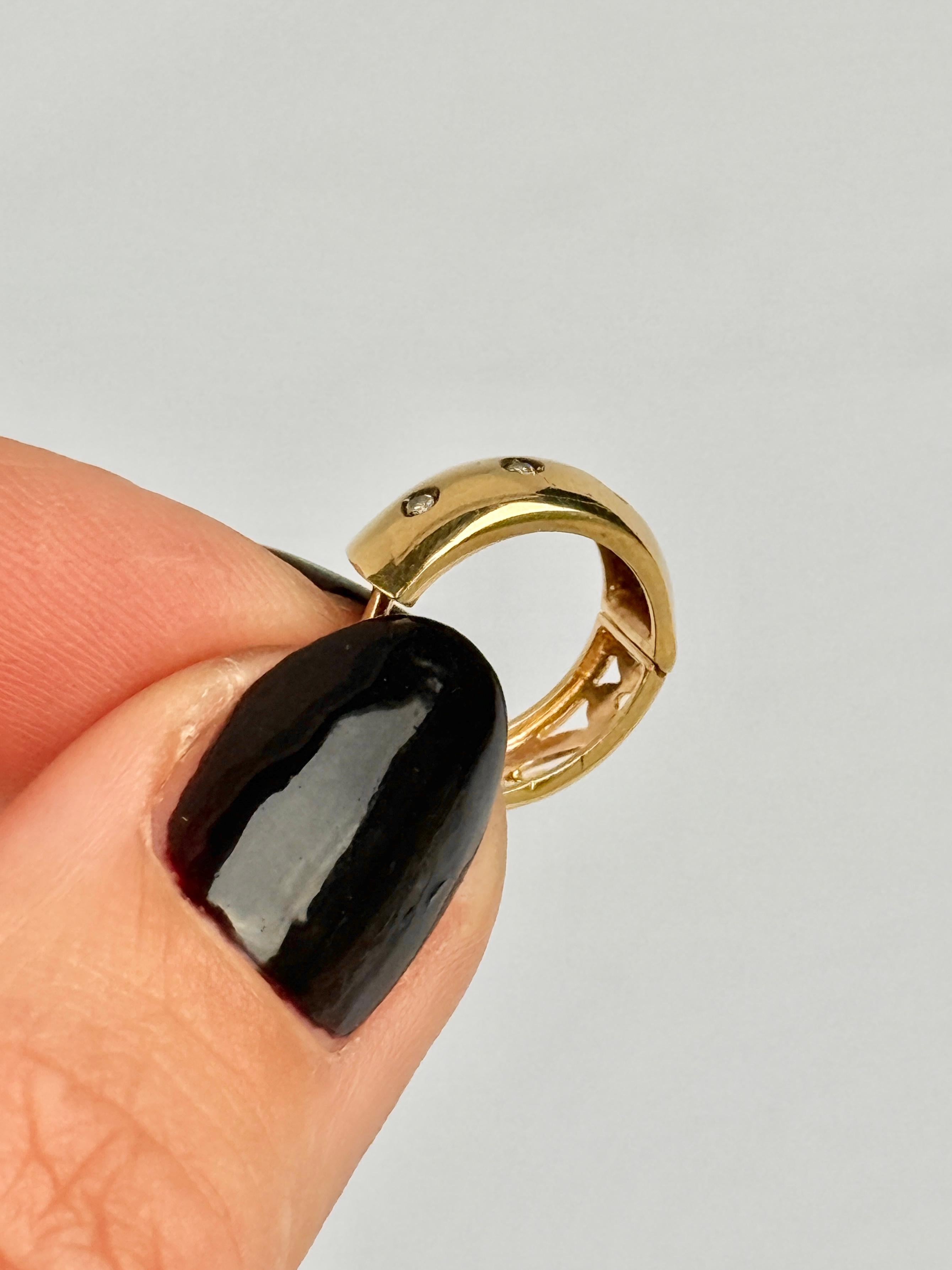 Gli orecchini sono realizzati in oro giallo 9ct. Si chiudono con una semplice clip a pressione. Questi cerchi sono a doppia faccia: su un lato sono incastonati tre diamanti da 1pt, mentre l'altro lato è caratterizzato da dettagli tagliati.