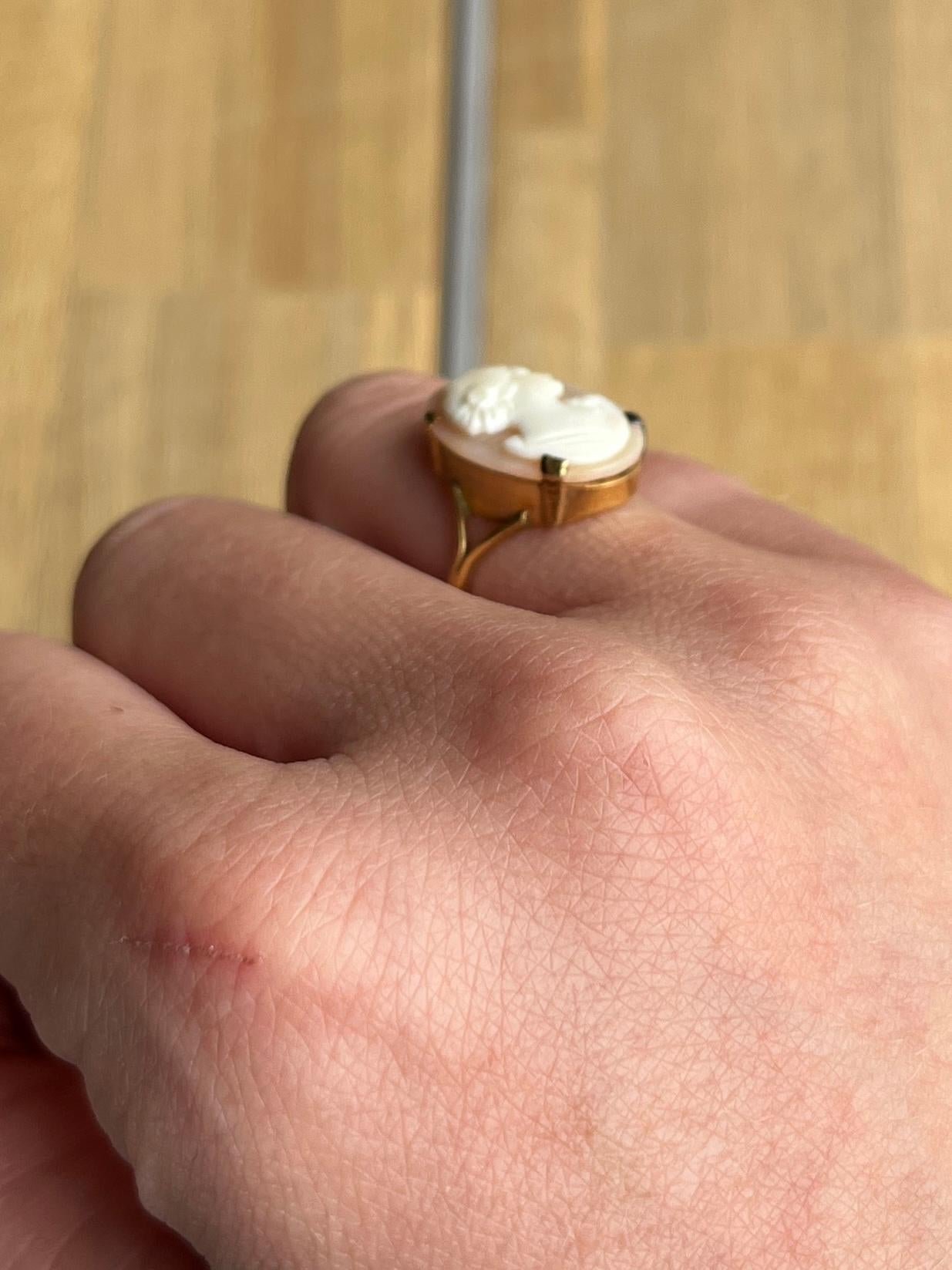 La conchiglia intagliata raffigura una bella donna ed è incastonata in semplici artigli; il tutto è appeso a un gambo d'oro a 9 carati. 

Misura dell'anello: L o 5 3/4 
Dimensioni del pannello: 12x17 mm

Peso: 2,6 g