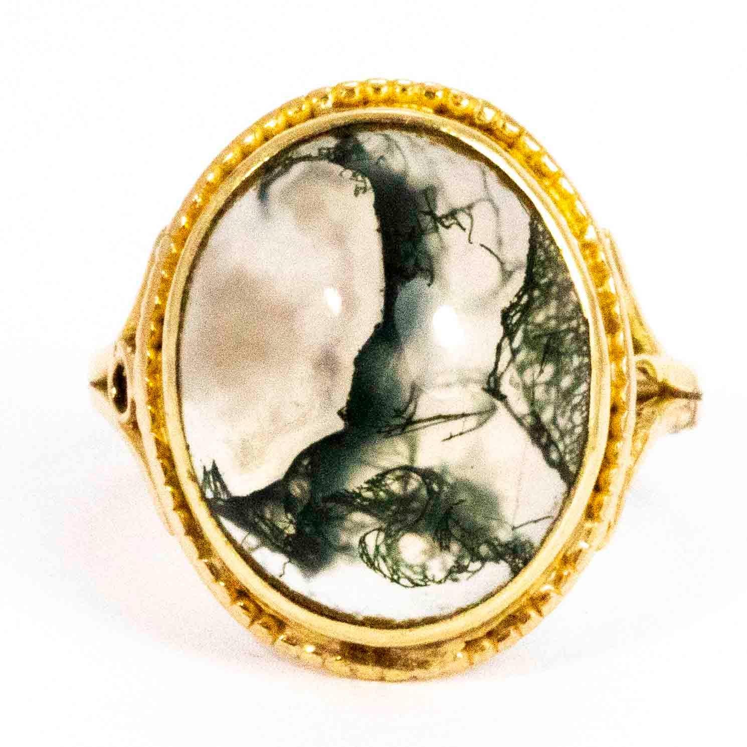 A beautiful vintage ring set with a large cabochon cut moss agate. The agate has wonderful intricate colouring which changes from every angle. The stone is surrounded by a superb scalloped border and set between elegant slit shoulders. Modelled in 9