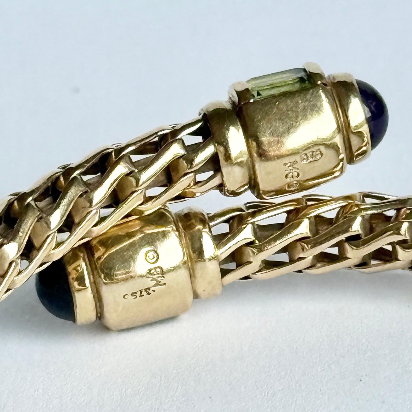 Dieser Armreif ist aus 9-karätigem Gold modelliert und mit Peridot- und Amethyststeinen verziert. Der Amethyst-Cabochon misst 75pts und die anderen Steine messen jeweils 30pts.

Innendurchmesser: 5cm (einstellbar)
Breite des Armreifs: 7 mm

Gewicht:
