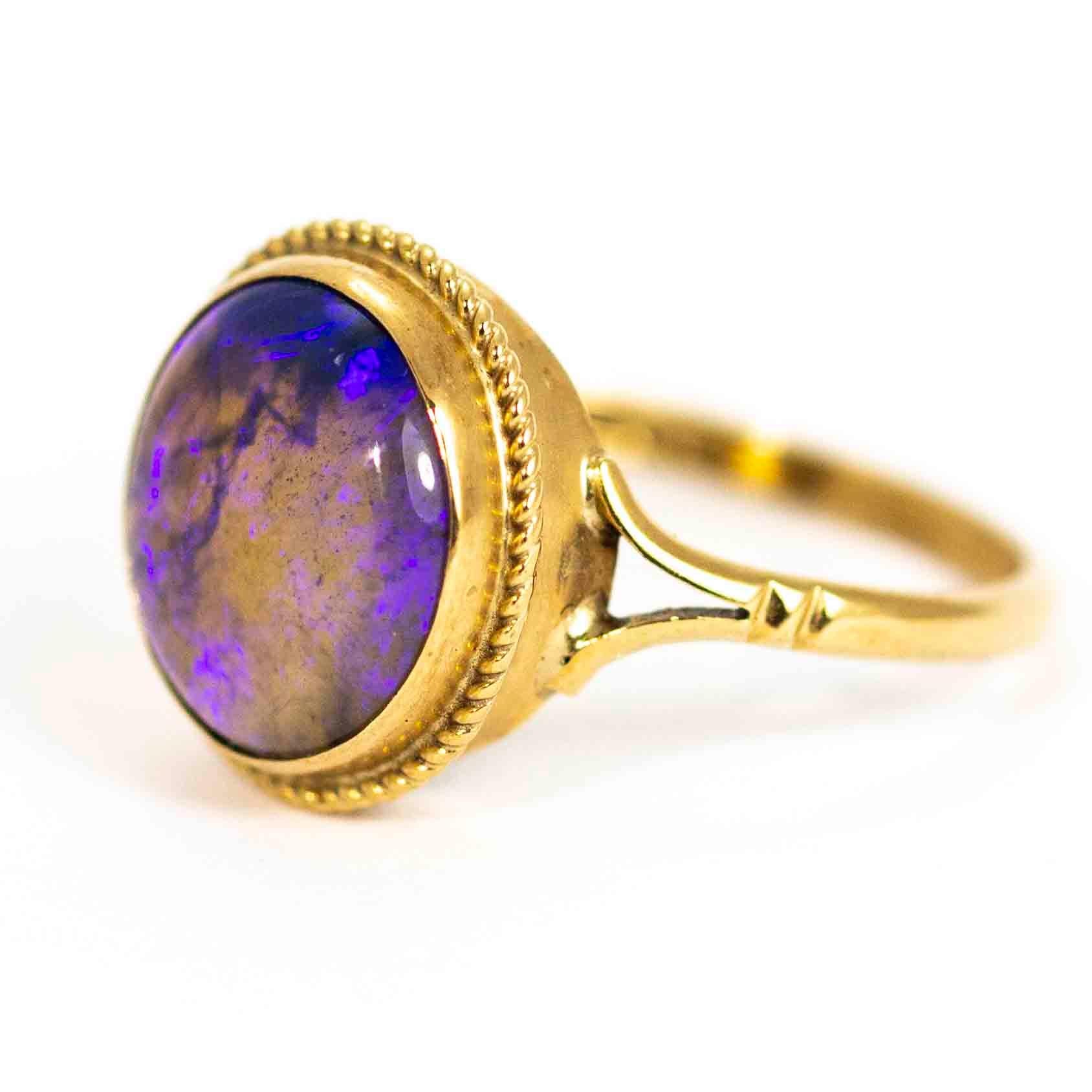 A stunning vintage ring set with a large round cabochon cut purple agate. The agate is superb, with a wonderful nebula of colours and sits between elegant spit shoulders. The stone setting is decorated with a fine twisted rope motif border. Modelled