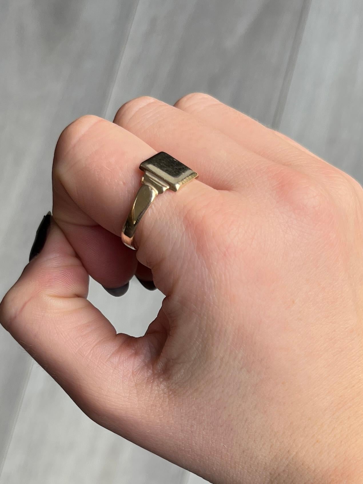This glossy 9ct gold signet ring has a square front and step shoulders. The ring has a very smooth and chunky feel to it. 

Ring Size: T 1/2 or 9 3/4 
Face Dimensions: 10x10mm

Weight: 3.8g