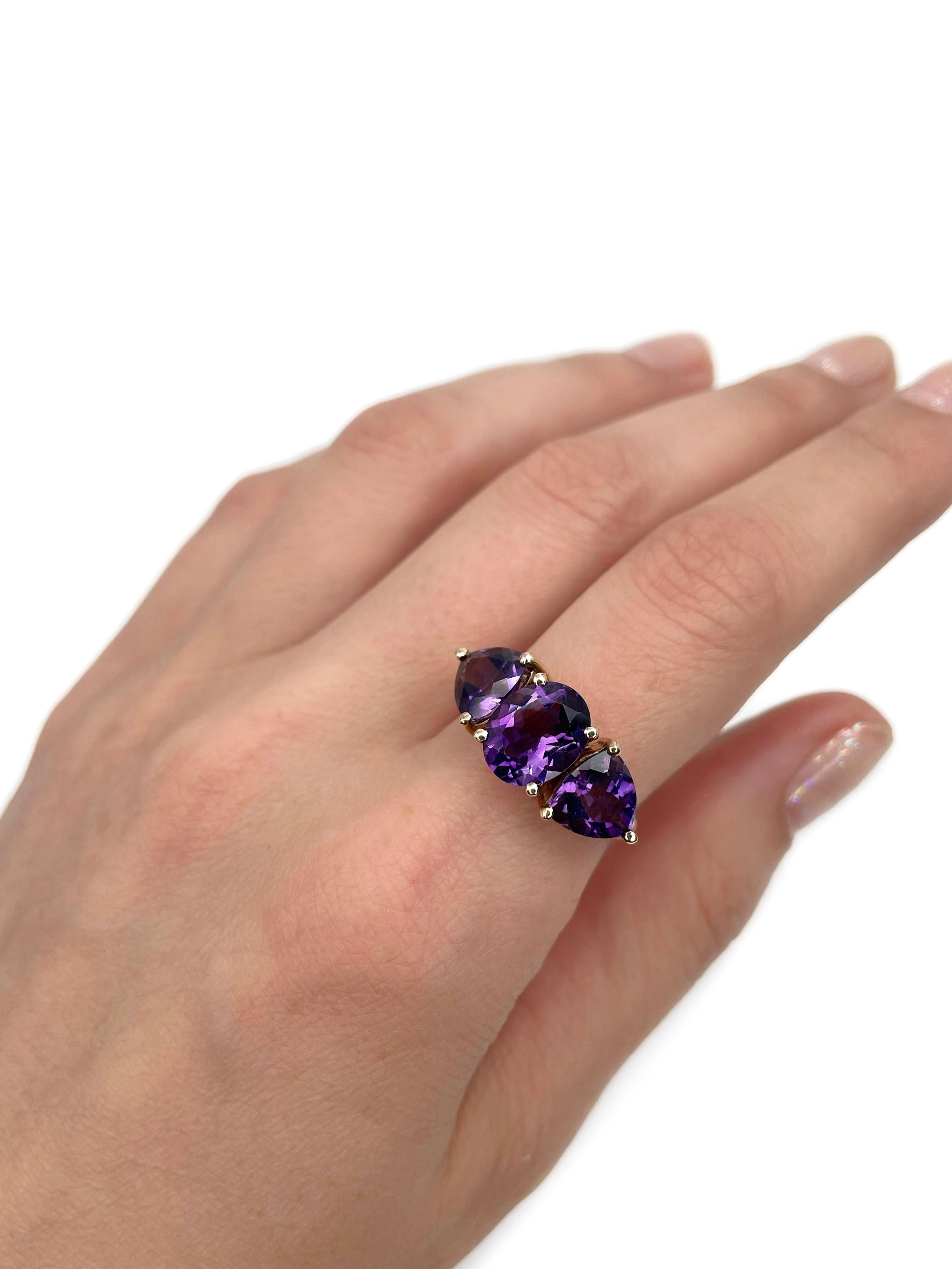 This is a vintage three-stone ring crafted in 9K gold. Circa 1980. 

The piece features amethysts (TW 5.60ct):
- 1 amethyst, oval cut, 2.40ct, P 6/4, VVS
- 2 amethysts, triangular cut, TW 3.20ct, P 6/4, VVS-VS

Weight: 3.77g
Size: 17.5 (US