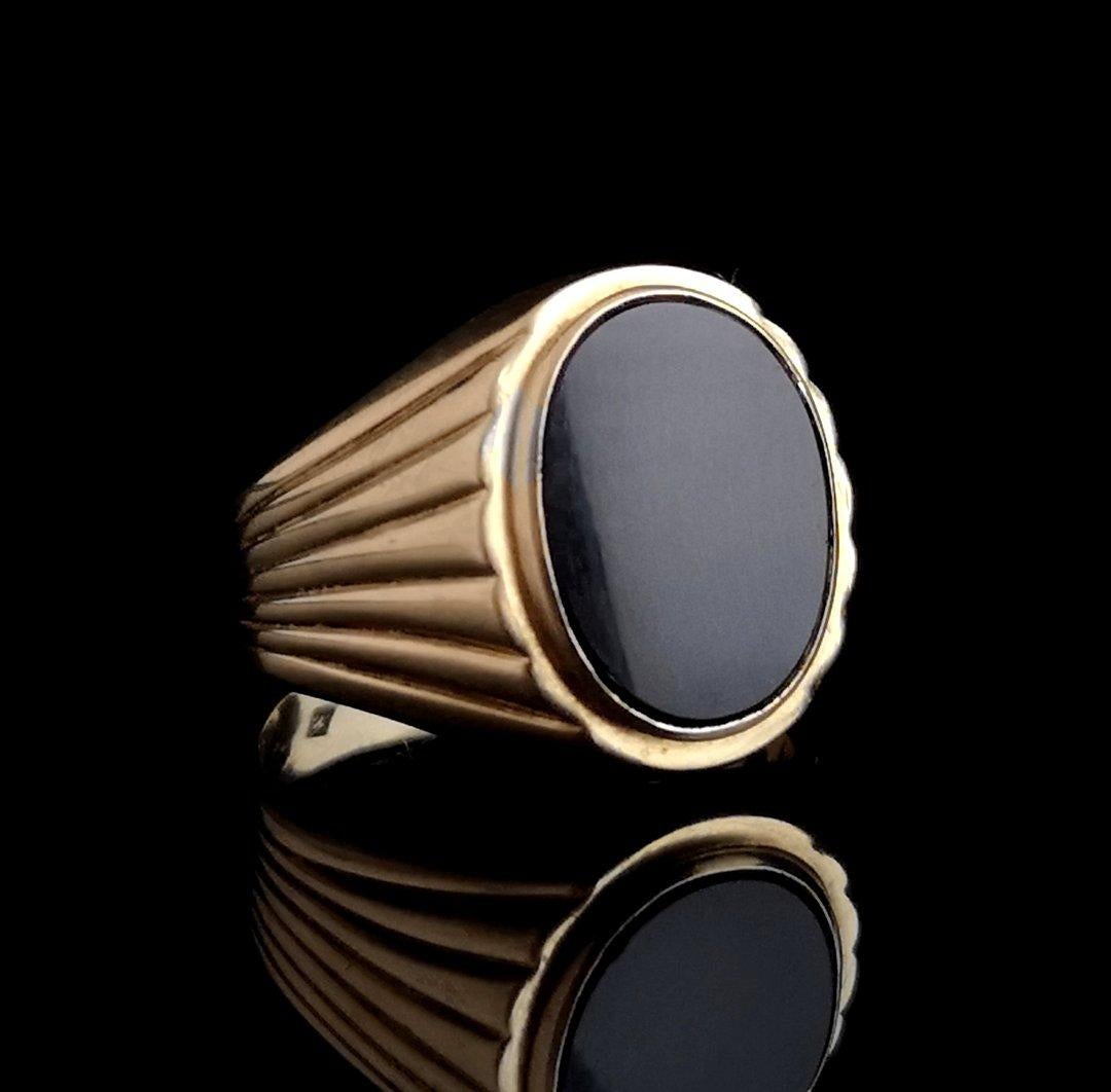 A handsome vintage 9 karat gold and onyx signet ring.

A huge polished, smooth onyx stone in a 9kt yellow gold rubover setting.

It has decorative grooved shoulders tapering down to the smooth gold band, this is a seriously chunky piece, a definite
