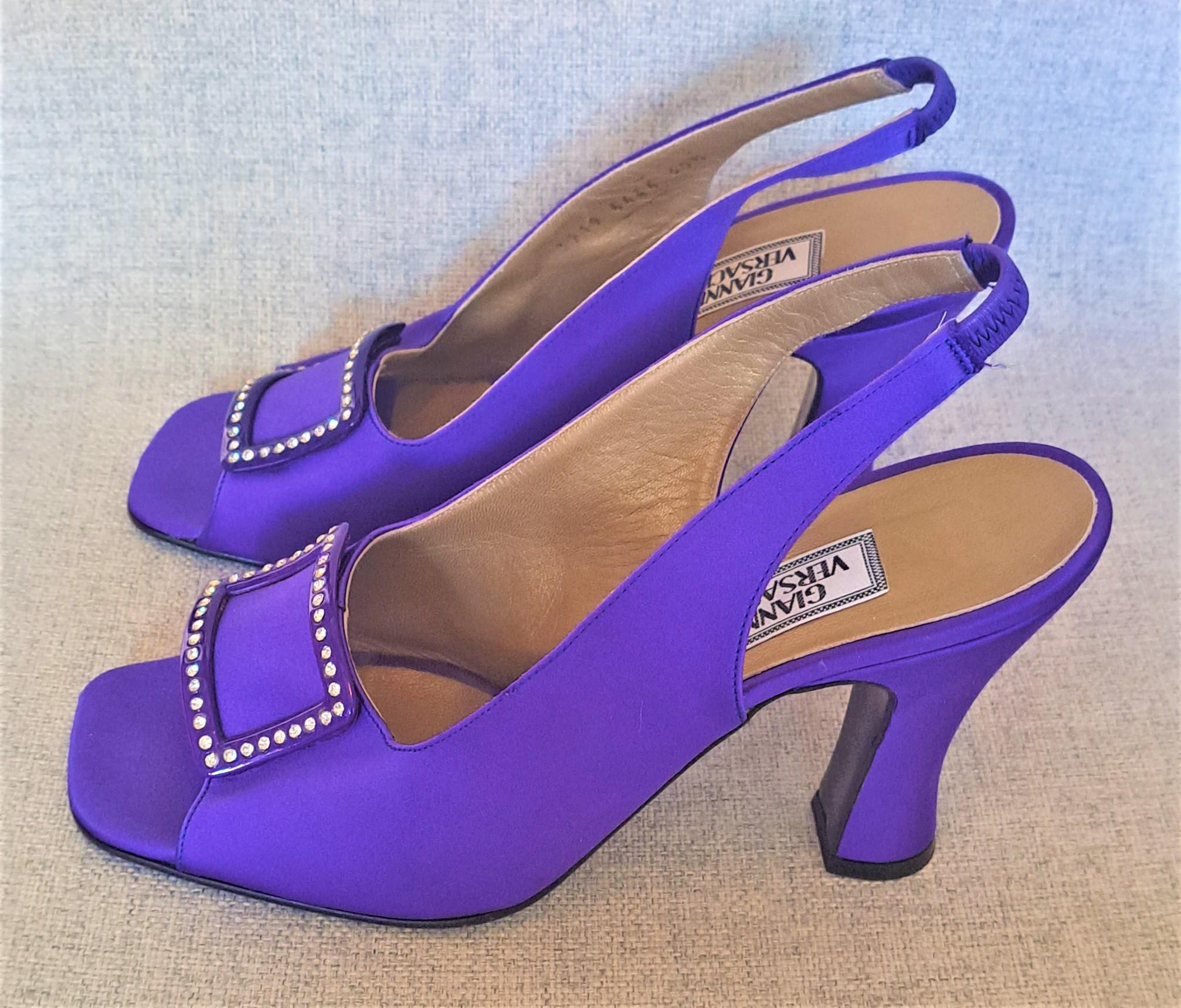 The vintage 90s Gianni Versace purple satin open-toe slingback with rhinestones is a glamorous and iconic shoe design from the fashion house of Gianni Versace. The shoe features a sleek and shiny purple satin material that is embellished with