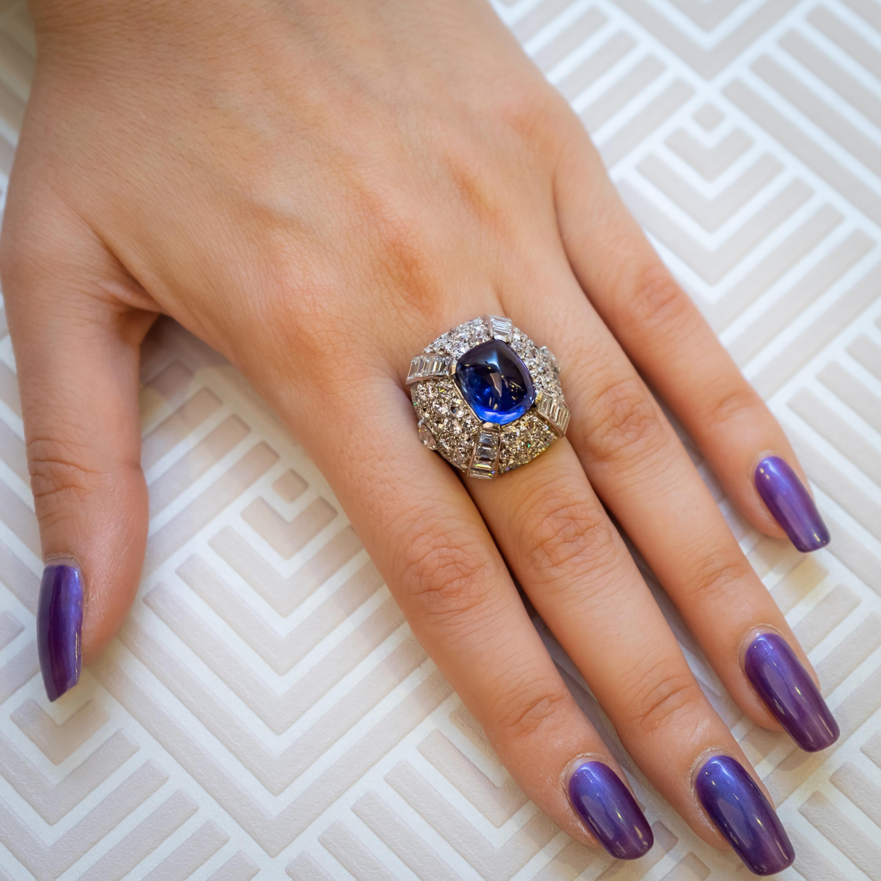 A vintage sapphire and diamond bombé ring, set with an unheated sugar-loaf cabochon sapphire, weighing 9.10ct, in the centre, with pavé set round brilliant-cut diamonds and channel set baguette-cut diamonds in the surround, with an estimated total