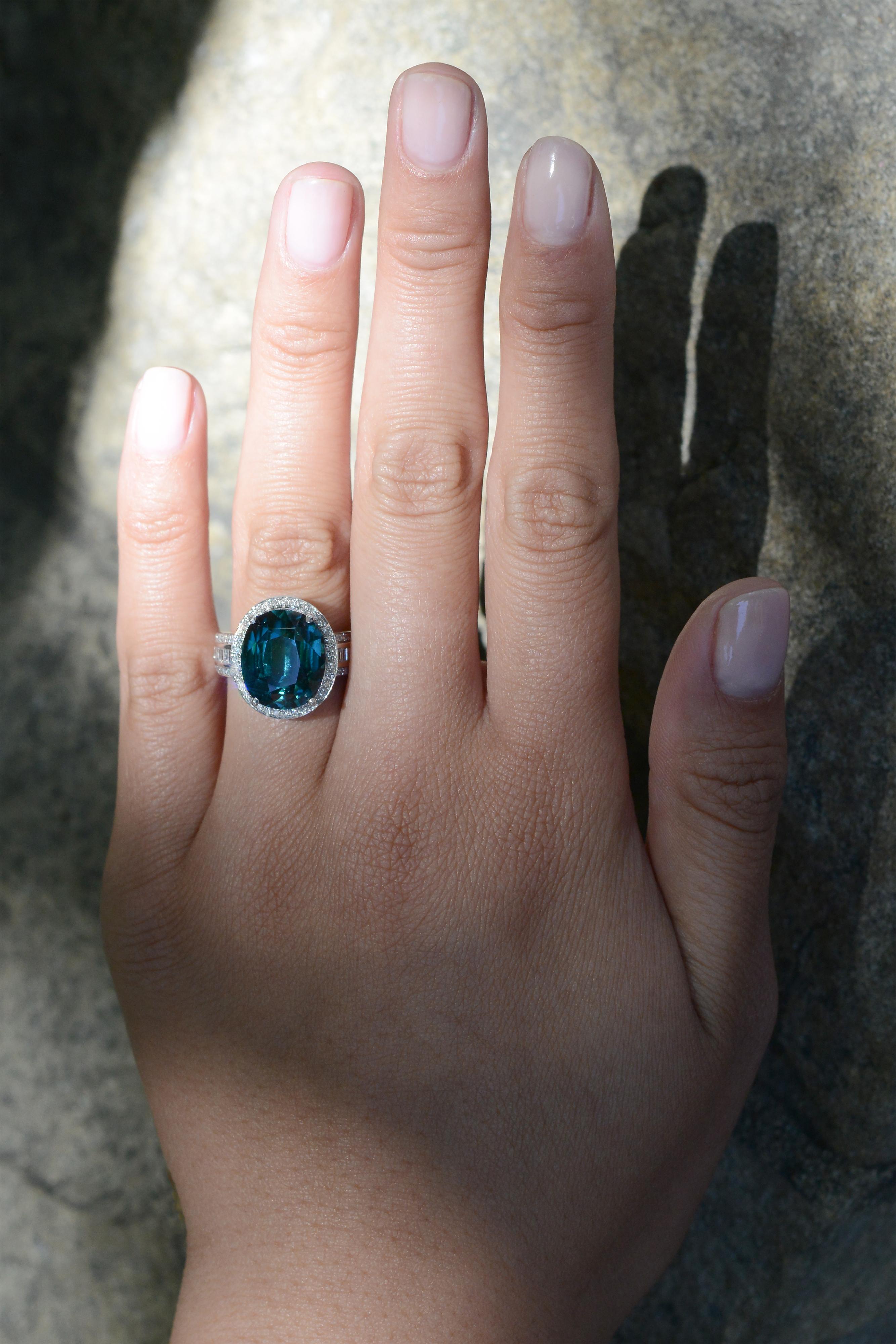 This exquisite estate cocktail ring boasts a treasured 9 carat oval tourmaline oval showcasing an alluring Mediterranean Sea color. Guaranteed to make a classy statement, the natural gemstone is embellished by the white gold and a halo of round