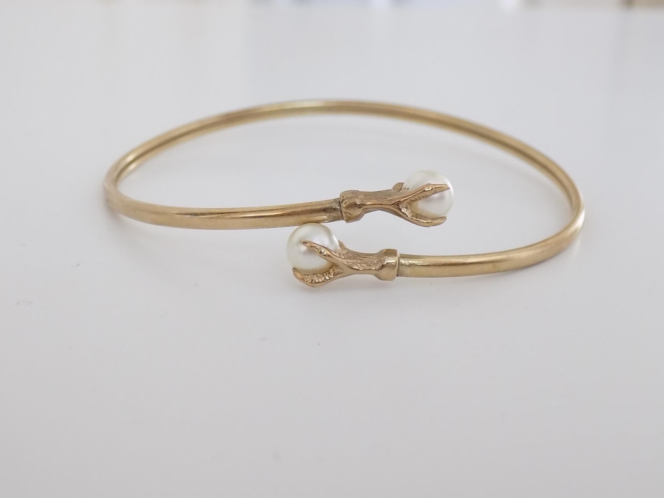 A Lovely Vintage 9 Carat Gold and faux Pearl Claw bypass  bangle. English Origin.

Width inside 63mm
Weight 5.6gr
Full English hallmark for Birmingham, 9 Carat Gold and dated 1965.

The bangle in very good condition and ready to wear.