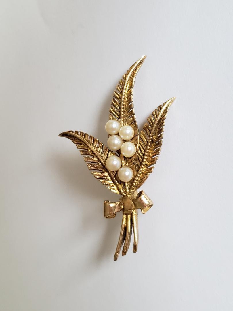 A lovely Vintage 9 Carat Gold and Cultured Pearl brooch in the form of a Spray of Leaves tied with a bow. 

Length 45mm.
Width 26mm.
Weight 4.4gr.

Fully hallmarked for 9 carat gold. 

The brooch complete with a secure rollover clasp.