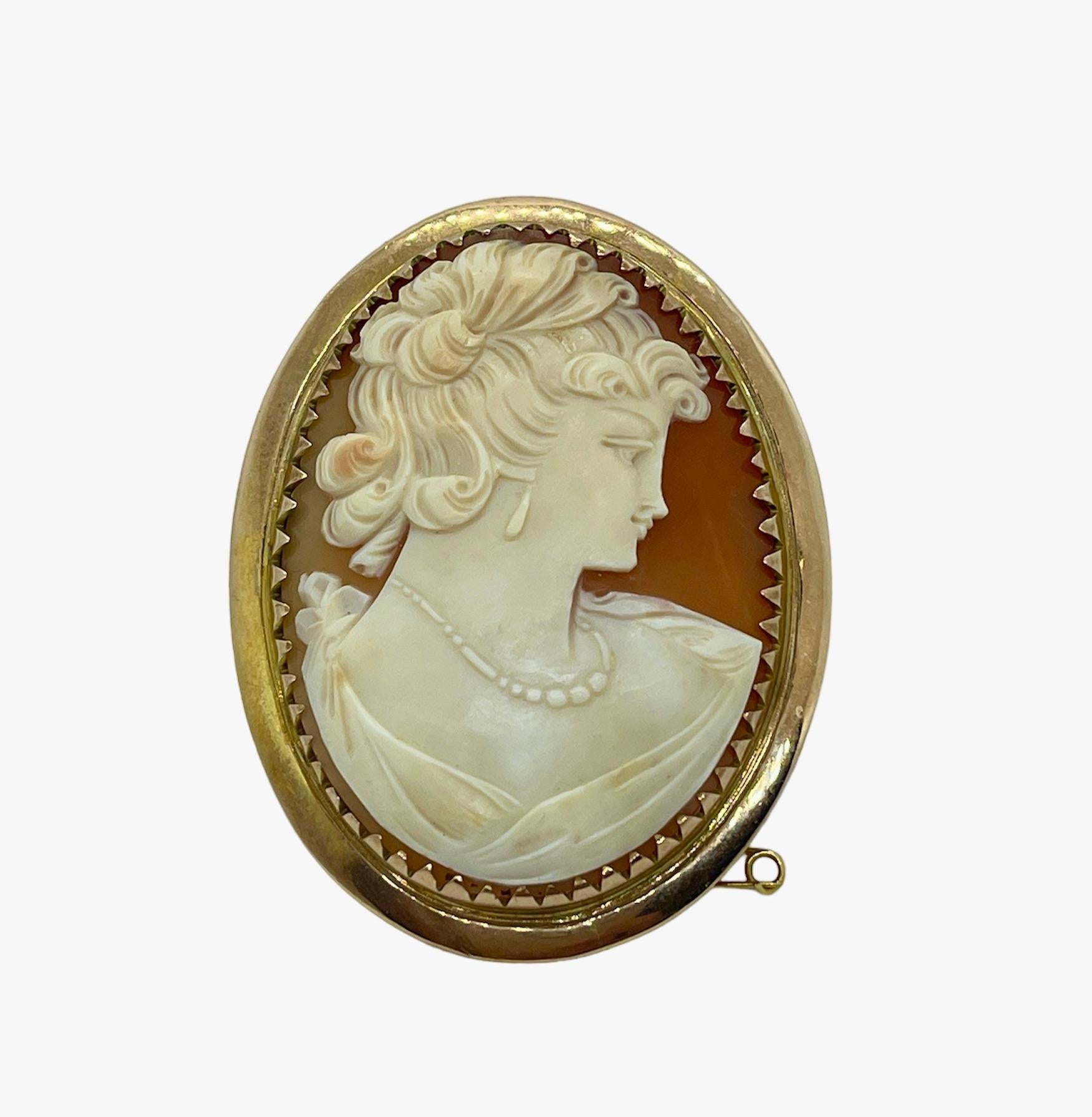 This brooch speaks quality.
It features a vintage Cameo that is hand carved in Sardonyx Shell (Conch shell) and depicts an elegant lady wearing a necklace and earrings.  Her curls are upswept and she has a whimsical, Mona Lisa smile!  Circa 1940s