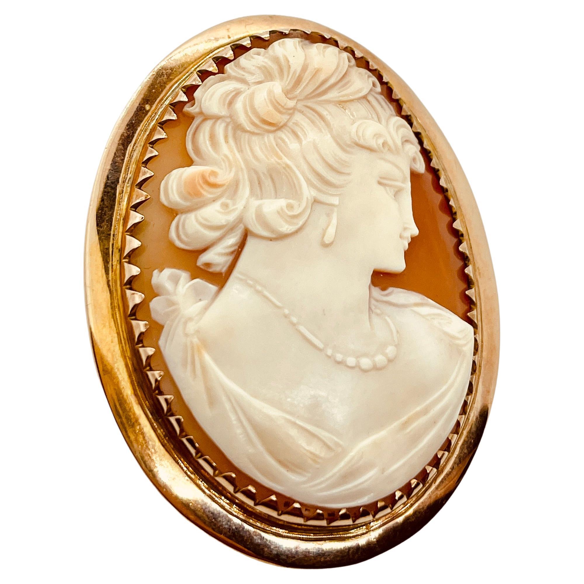 The Lady Wearing Jewels.
This vintage brooch features a Cameo that is hand carved in Sardonyx Shell (Conch shell) and depicts an elegant lady wearing a necklace and earrings.  Her curls are upswept and she has a whimsical, Mona Lisa smile!  Circa