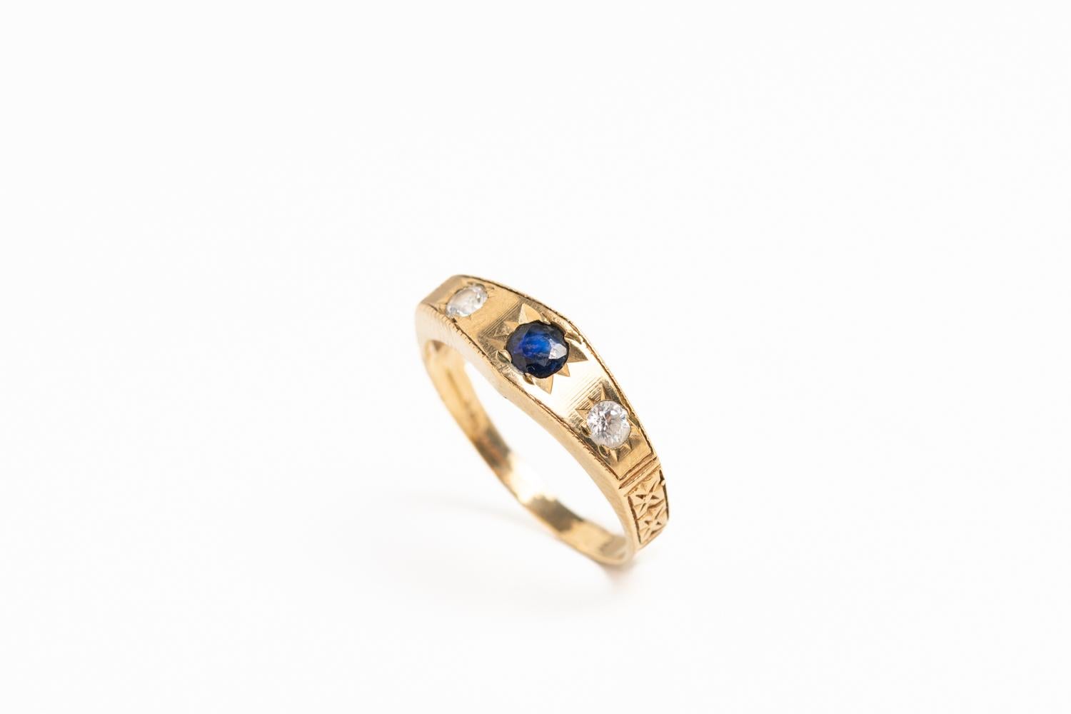 Elegant vintage 9ct gold sapphire and diamond ring. The ring has two sparkling diamonds on each side with a sapphire in the centre. Decorated with a floral motif on the band. Fully hallmarked for 9ct gold with a London assay mark. 

Size: K