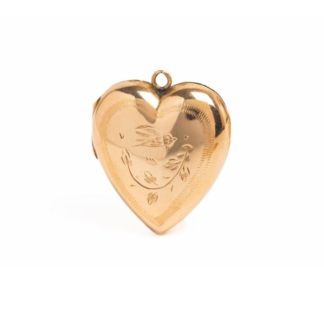 This beautiful and charming vintage Edwardian style 9ct gold front & back heart locket was made circa the 1970s. The heart shaped locket depicts a swallow in the flight surrounded by a garland of flowers. It has been engraved on front side and
