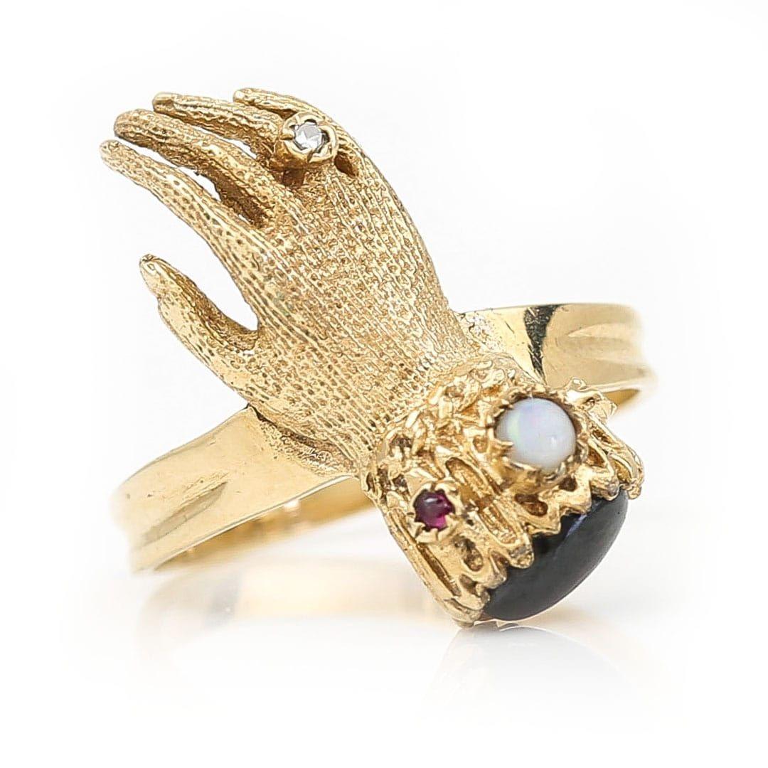 A Georgian inspired 9ct yellow gold vintage opal, garnet, ruby and diamond hand ring dating from 1973. The head of the ring styled as an 19th century textured gloved hand with a diamond set ring to the wedding finger and the cuff detailed with an