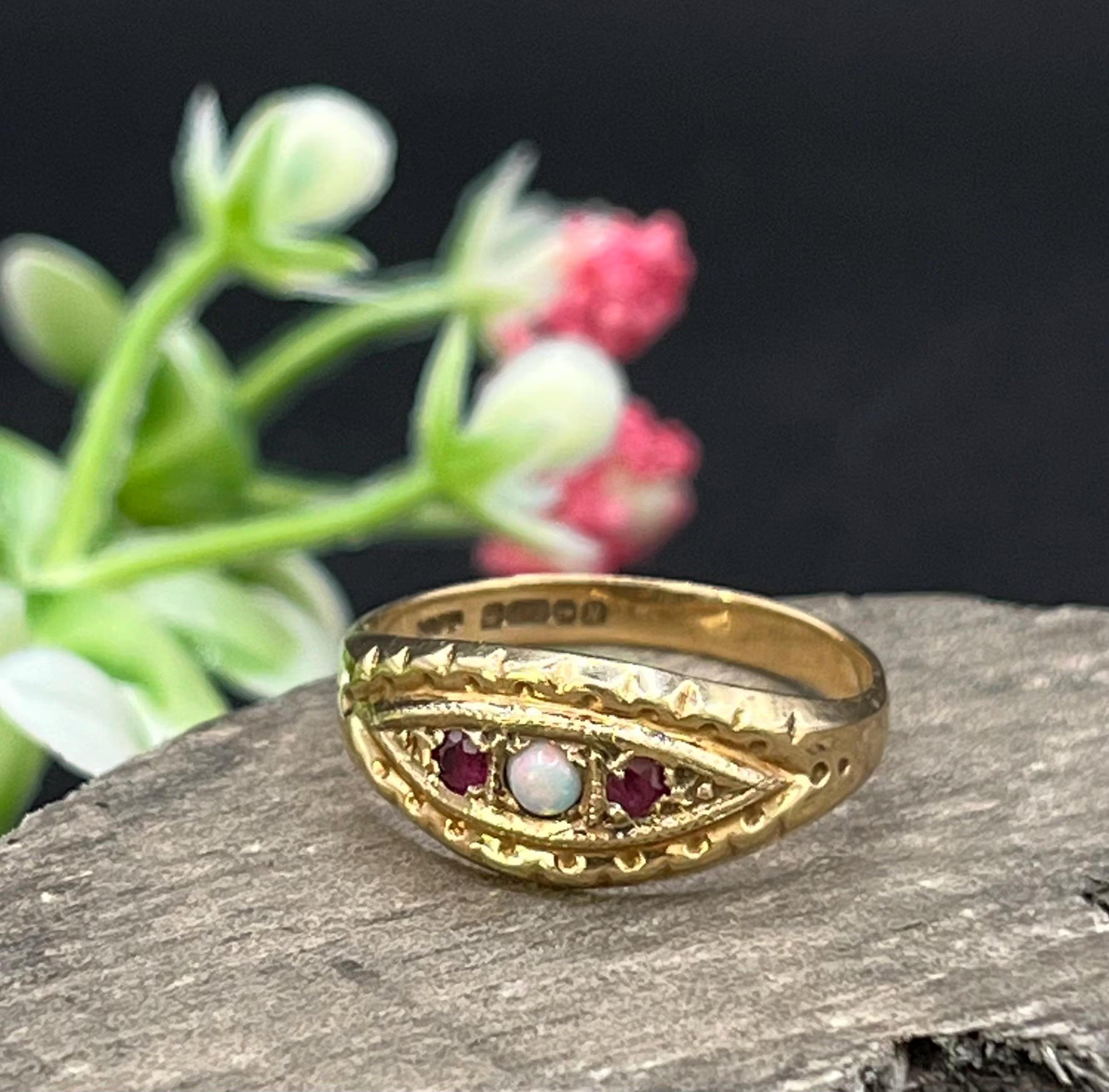 Bague vintage 

Poin�çonné 9ct Birmingham 1987

Makers Mark VAFP

Bague vintage en or 9ct, poinçonnée à Birmingham. Elle est composée d'une opale centrale et de deux rubis de part et d'autre. Les épaules ornées ajoutent des détails subtils et du