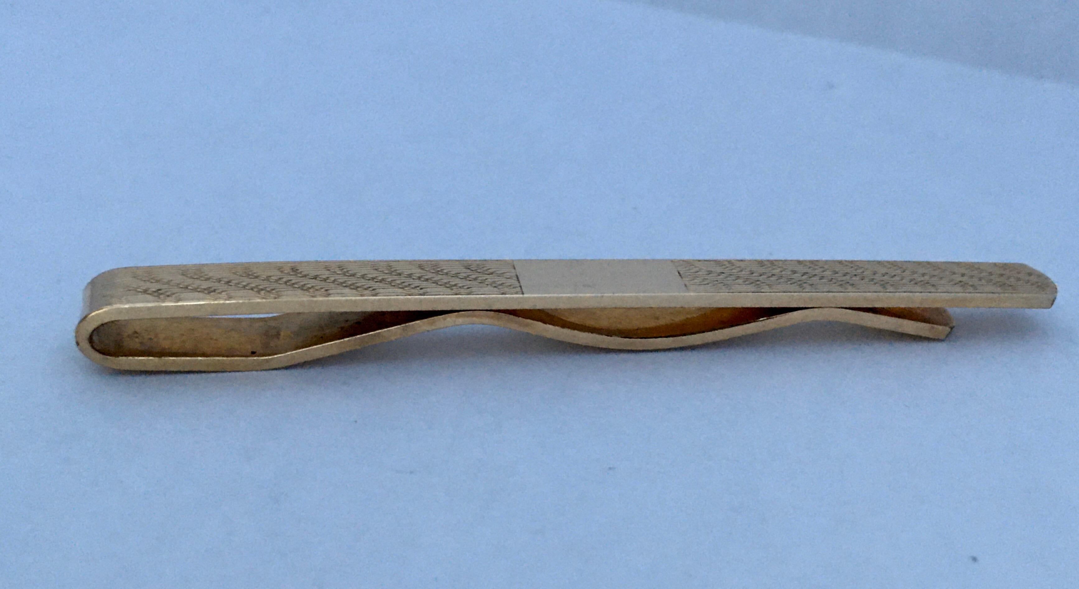 This is a pre-owned condition 9ct yellow gold vintage tie clip.

The tie clip has a wavy striped pattern and a plain gold on the centre. It measures 70mm length 6mm width. It weigh 6.9 grams. 

Please study the images carefully as form part of the