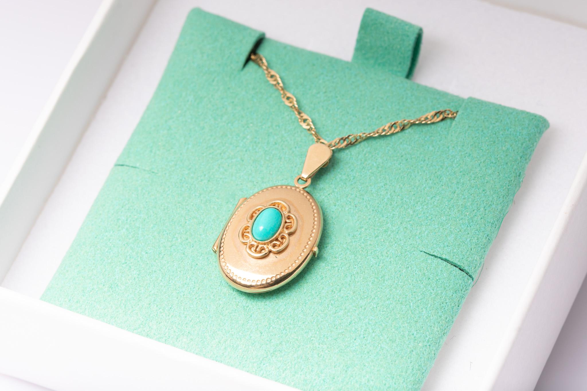 A charming vintage 9ct gold and turquoise locket pendant and a chain circa 1970s. The front of the locket is decorated with a light blue turquoise cabochon surrounded by a scrolled design inspired by reminds by Victorian floral motifs. Turquoise