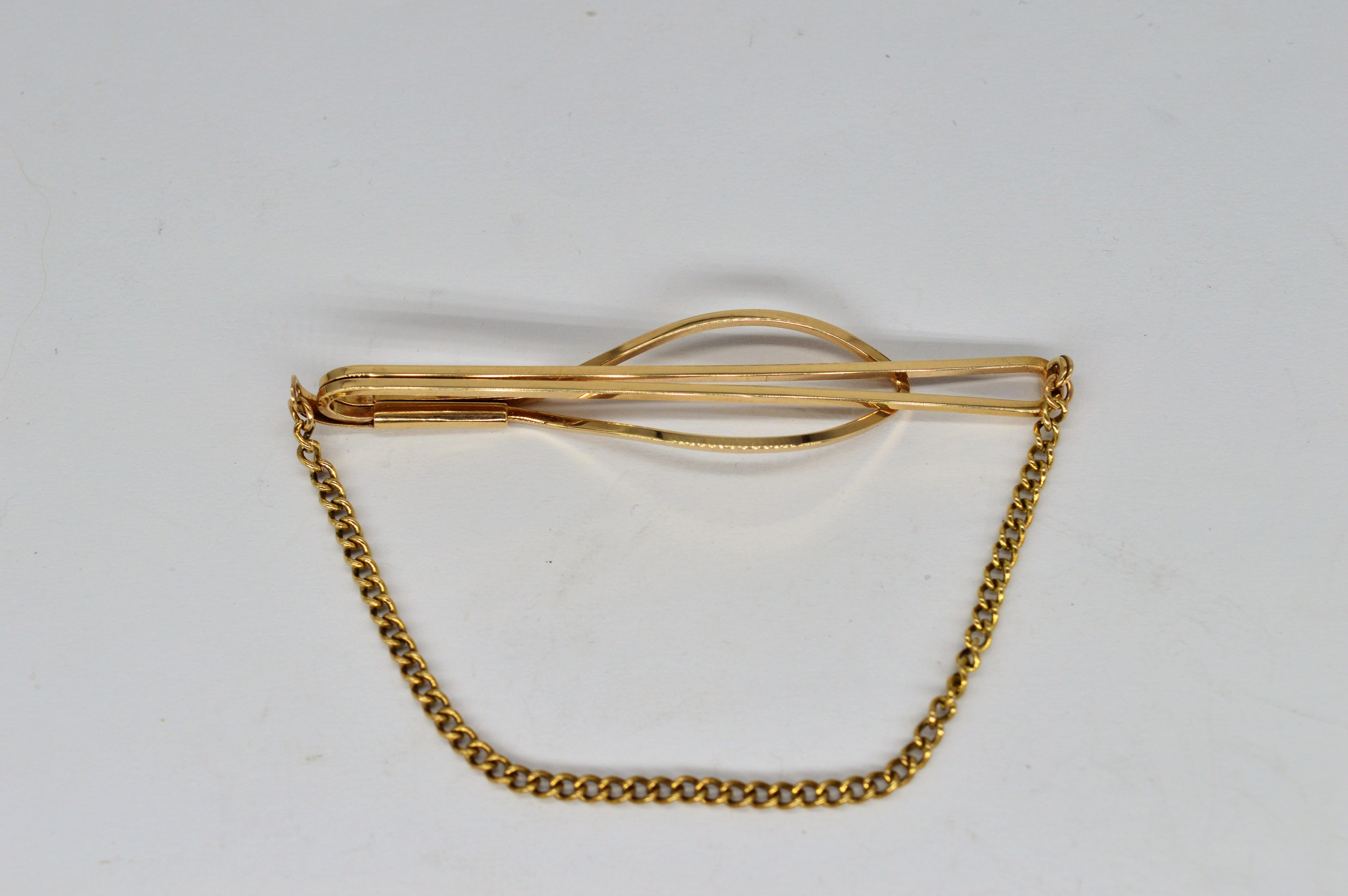 A vintage 9ct gold tie clip with a stylish chain

Classically designed with a chain to hold down your tie

5.10g

We have sold to the set of Hit shows like Peaky Blinders and Outlander as well as to Buckingham Palace so our items are truly fit for