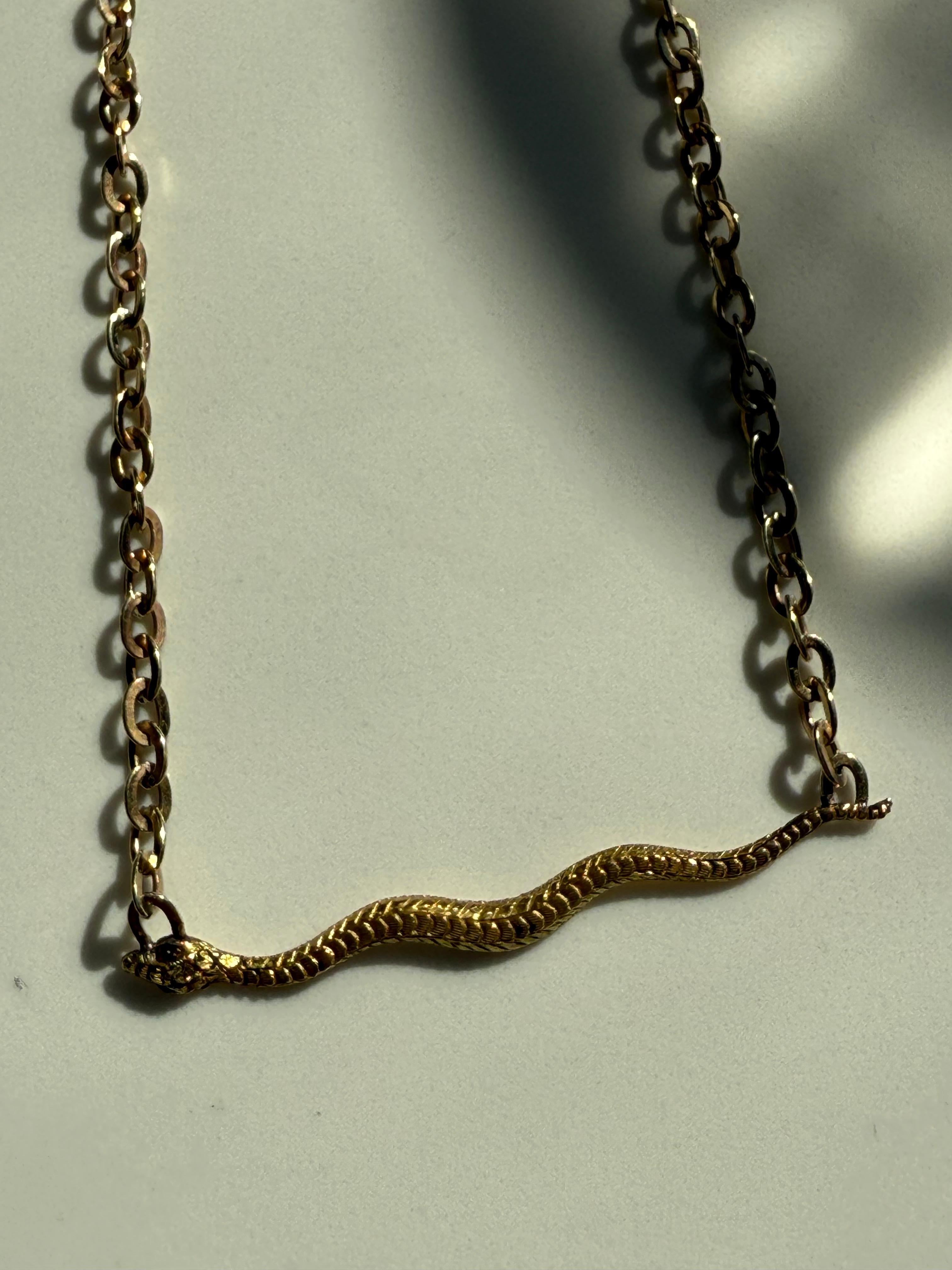 Realizzata in oro giallo 14 carati e con una catena in oro giallo 9 carati, questa collana con serpente antico affascina con le sue scaglie dalla texture sapientemente dettagliata e la sua catena unica e antica. Ci sono 2 occhi rotondi di rubino
