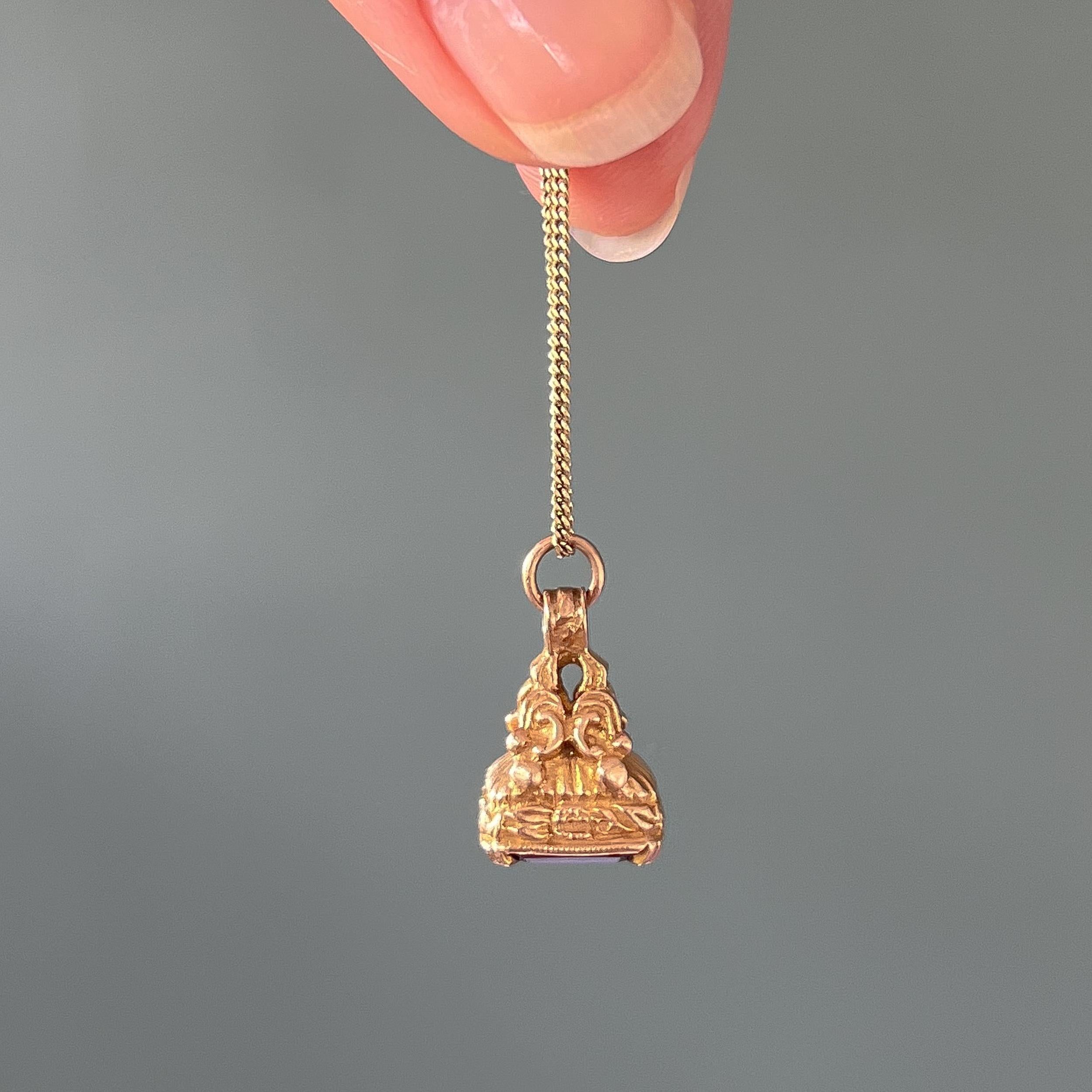 This lovely fob charm pendant is made of 9 karat gold and it carries a plate of dark red carnelian at the bottom. The charm is nicely detailed with scrolling gold and engraved details. This pendant is a miniature fob as they were made in Georgian