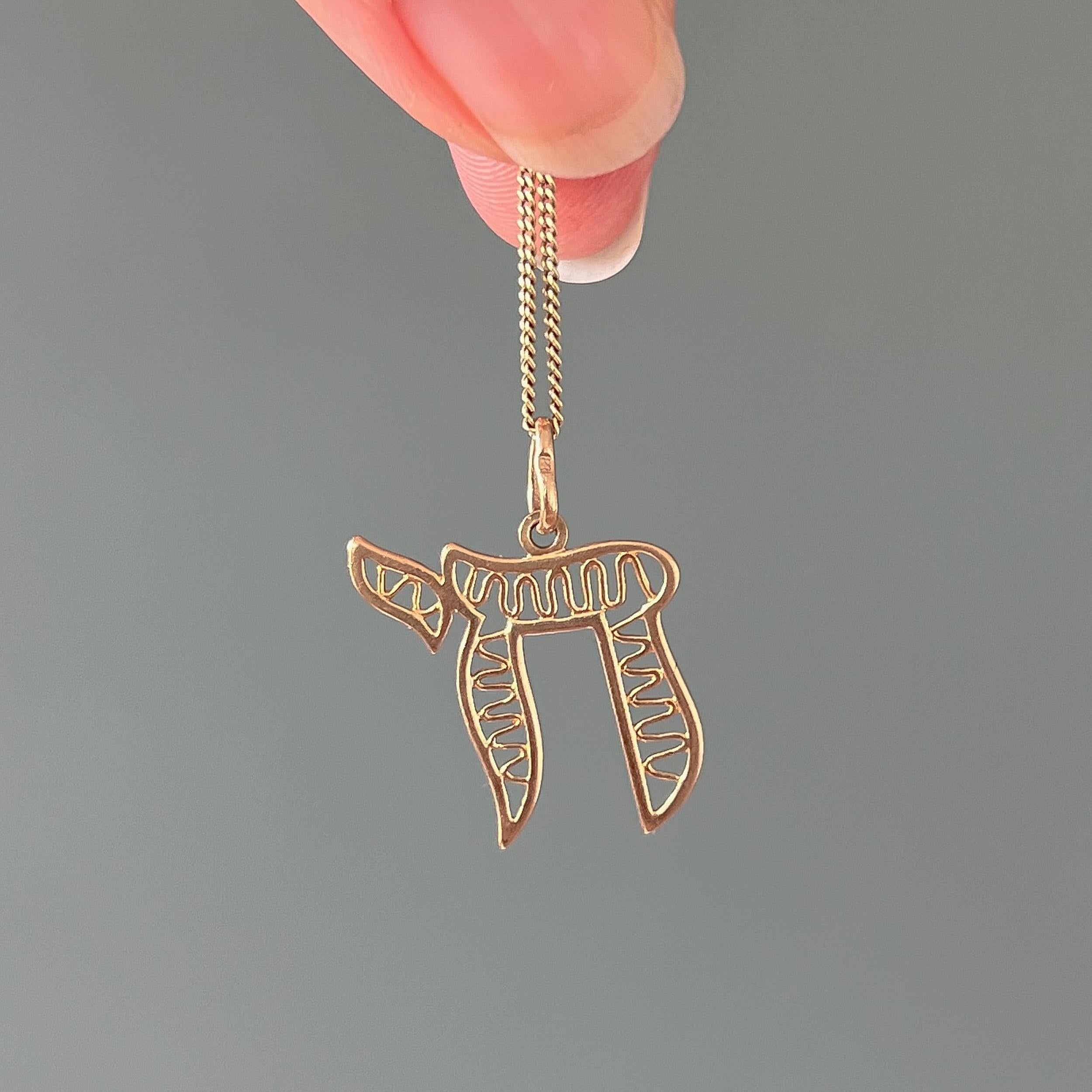 A vintage 9 karat yellow gold Chai amulet symbol charm pendant. The Chai, pronounced as 'khai' is a known Jewish and Hebrew word, symbol, amulet and a blessing. A symbol that was first seen in the Middle Ages in Spain became an integral part of