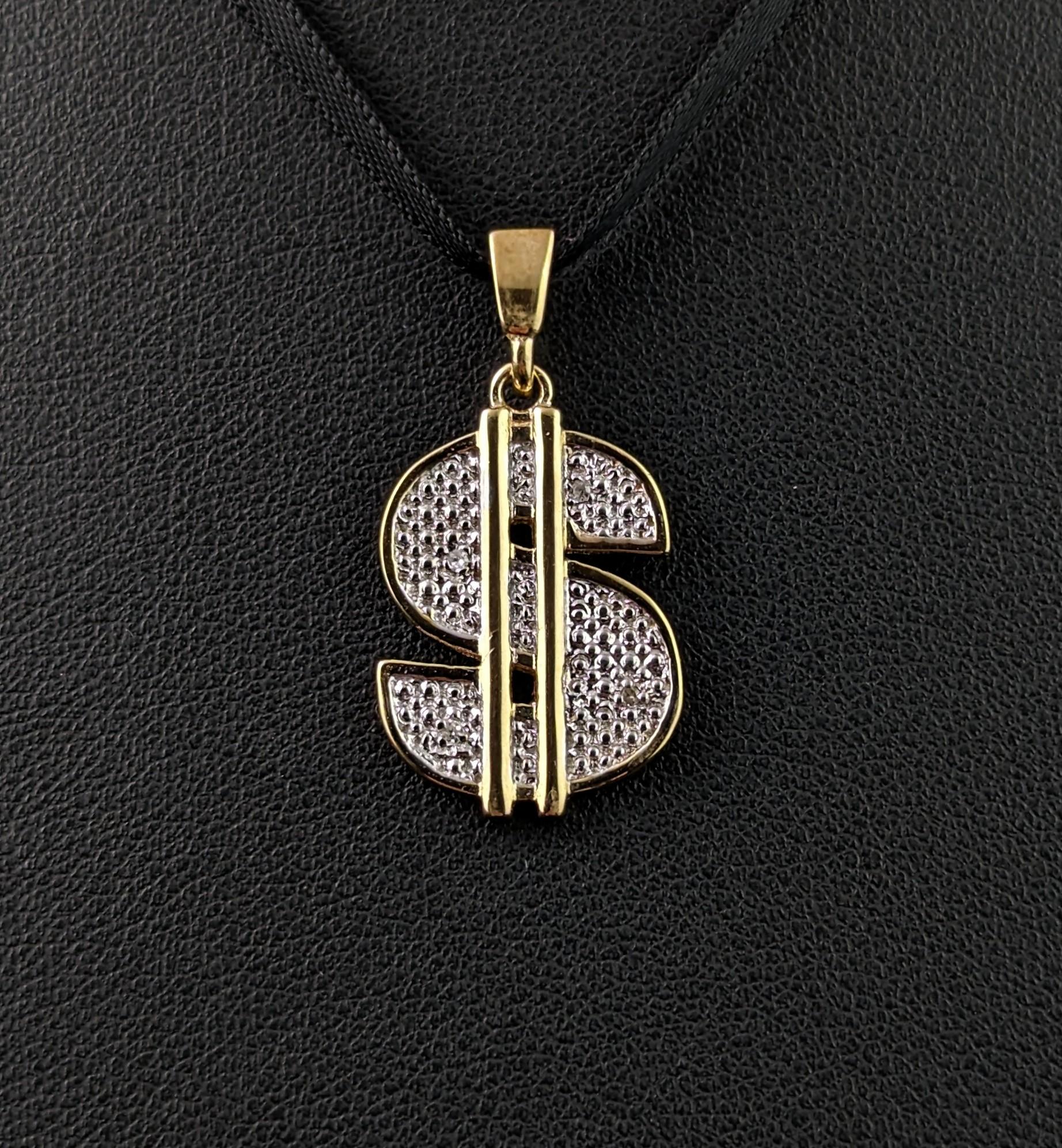 A fun vintage 9ct gold and Diamond dollar sign pendant.

This stand out pendant looks great as part of a neck mess or on its own on a gold chain necklace.

It is crafted in rich 9ct yellow gold and cool 9ct white gold, the white gold sections to the