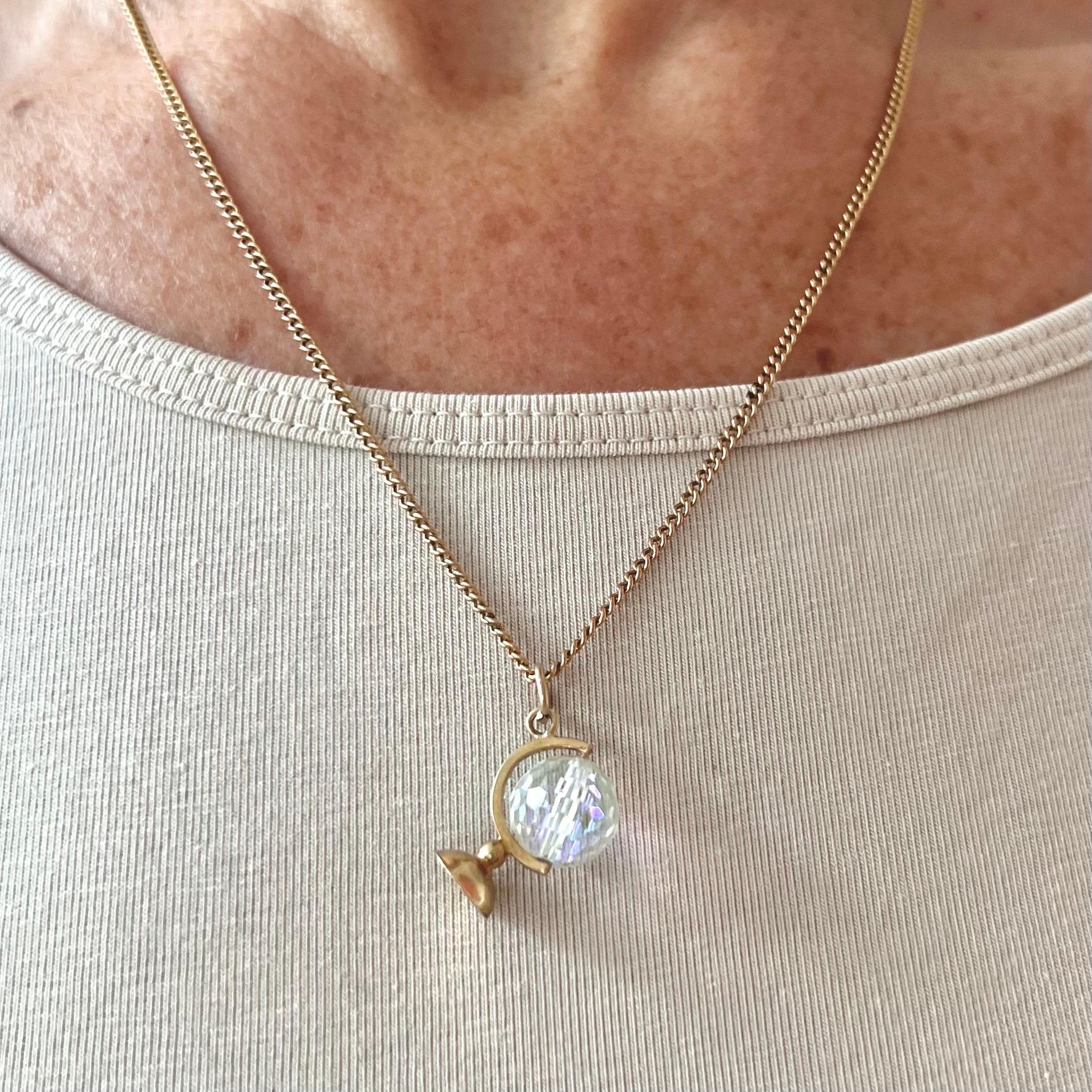 A vintage 9 karat yellow gold glass globe charm pendant. The charm is beautifully detailed with a spinning glass globe with a prism of light. 

A prism is a clear, triangular device made up of plastic or glass (or any transparent material). When
