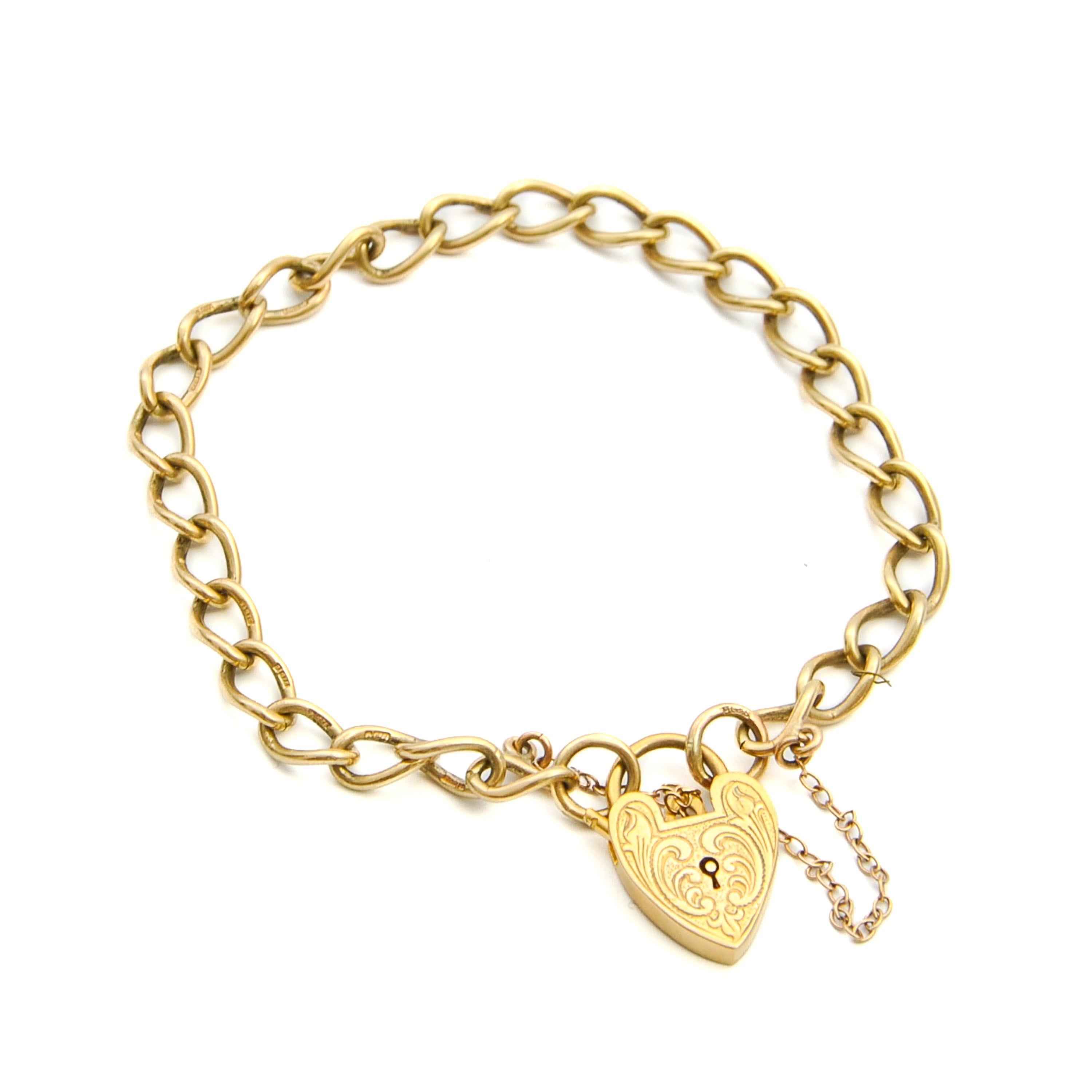 A lovely padlock curb chain charms bracelet set with an engraved heart closure. The curb chain and heart are created in 9 karat gold. The heart-shaped padlock has beautiful engravings on the front and is fitted with a safety chain. The bracelet set