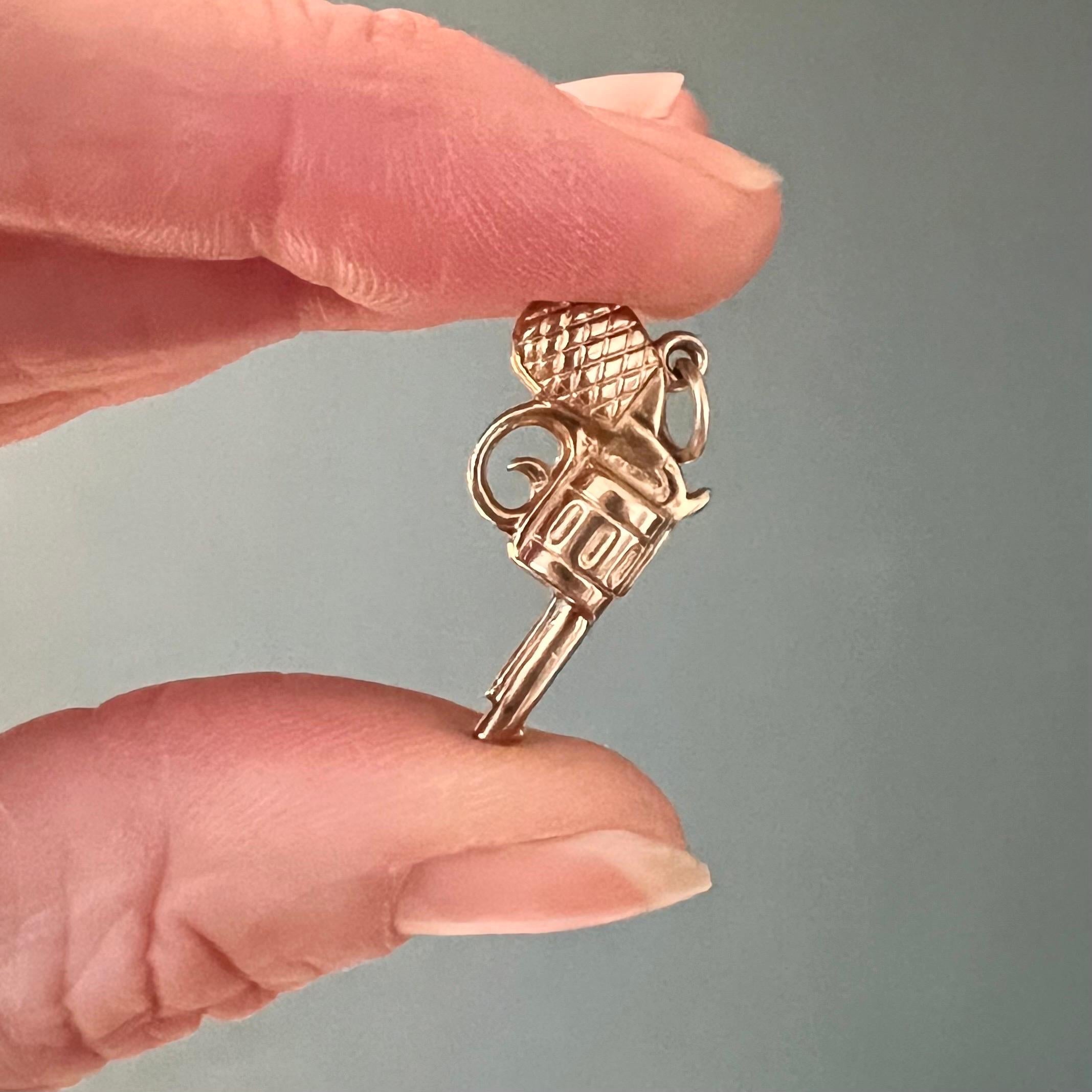 This is a vintage 9 karat yellow gold revolver gun charm pendant. The handgun is detailed with one barrel and one revolving cylinder with multiple chambers - each holding a single cartridge for firing. The grip panel has nice diamond-shaped