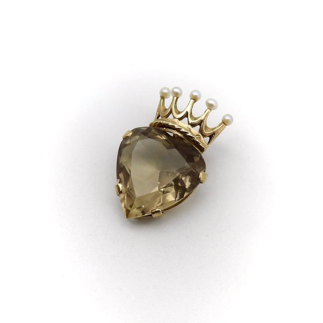 This gorgeous pendant features a heart-shaped smoky topaz, topped with a 9k gold crown. The large quartz contains facets that bring out the stone’s warm, buttery tones, and the gold crown is adorned with five small pearls and hand engraved detail.