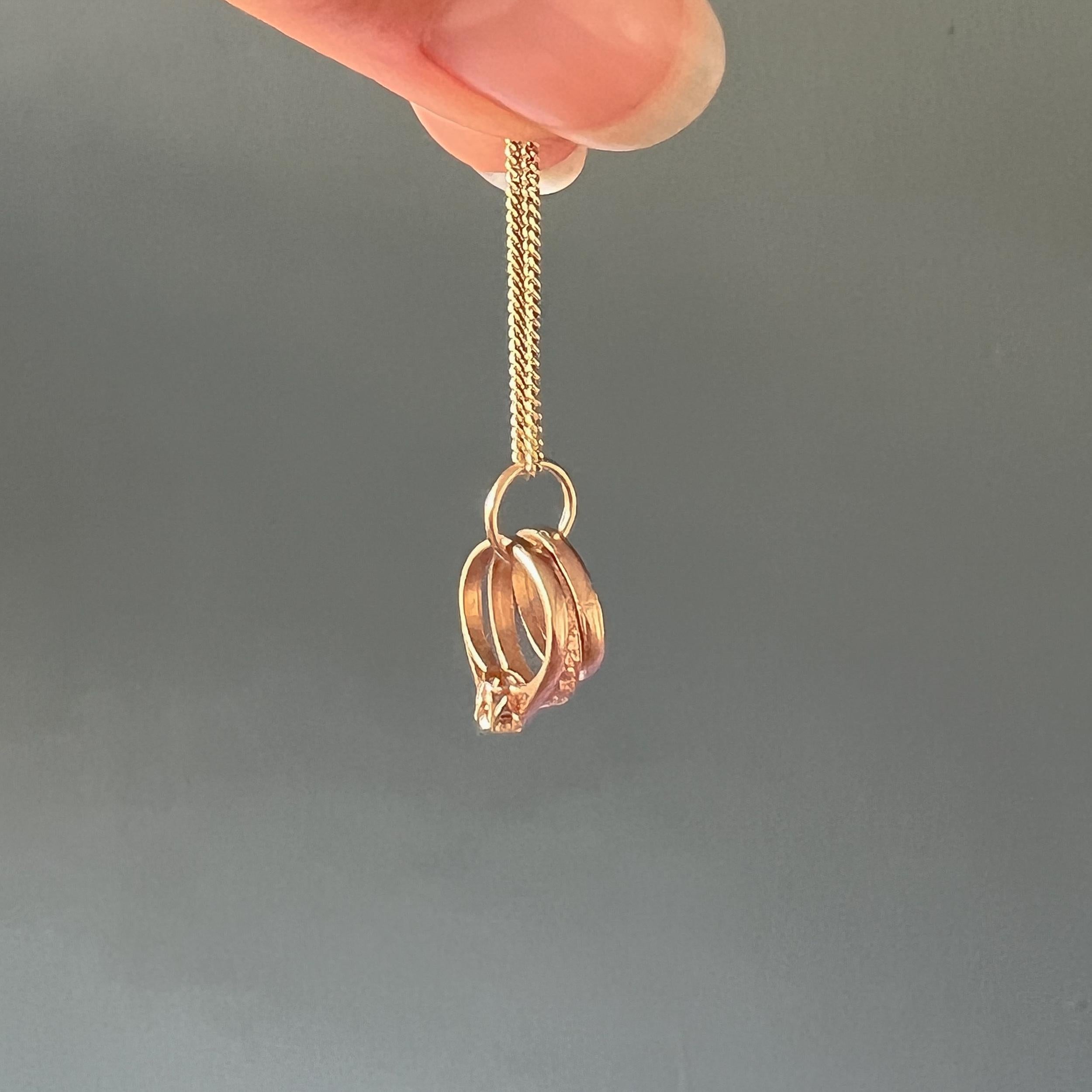 Il s'agit d'un pendentif vintage en or jaune 9 carats avec des anneaux de la trinité en forme de breloque. Ces bagues sont joliment détaillées et réalisées dans des tons d'or et d'or jaune. La première bague a une pierre claire qui rappelle un