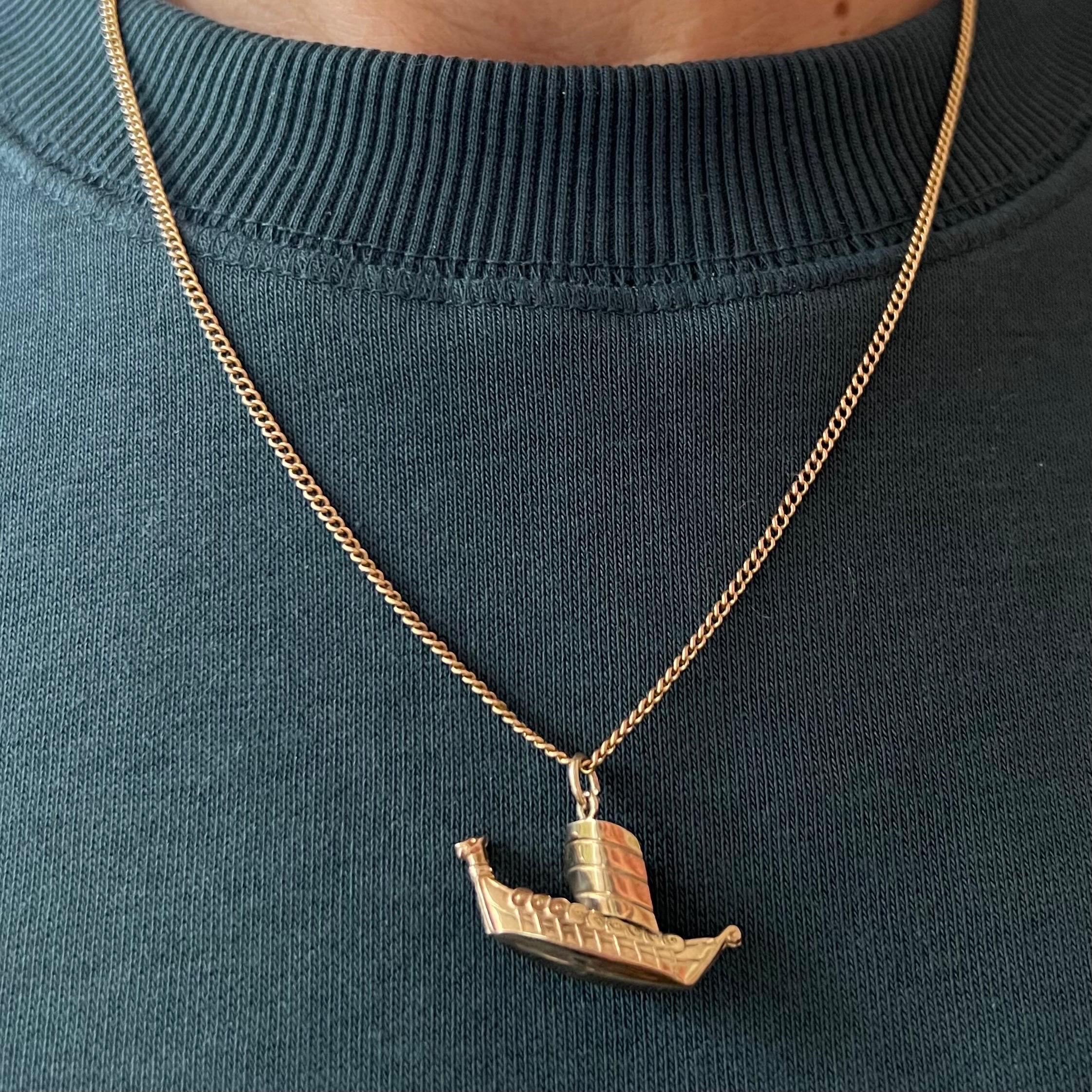 A vintage 9 karat yellow gold raiding viking dragon ship charm pendant. The vessel is beautifully detailed with a large sail, 'wooden' planks, shields on the sides, oars and a fierce dragons head on the stern. 

Viking ships were seagoing vessels