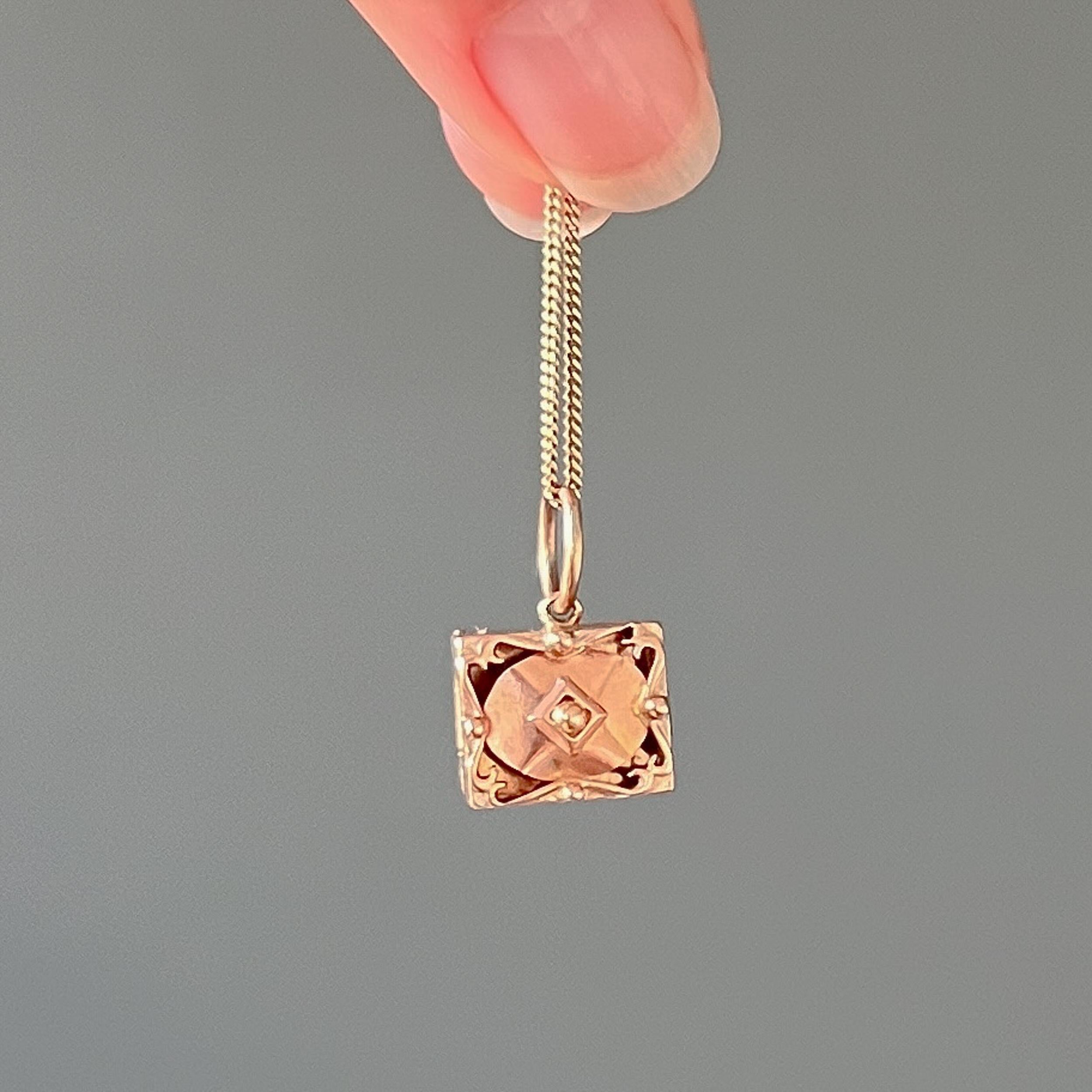 A vintage 9 karat yellow gold box charm pendant. This charm is nicely detailed and beautifully made with gold and rose gold tones. The front has an openwork design and features raised gold details. The box can be opened and closed - you can put a