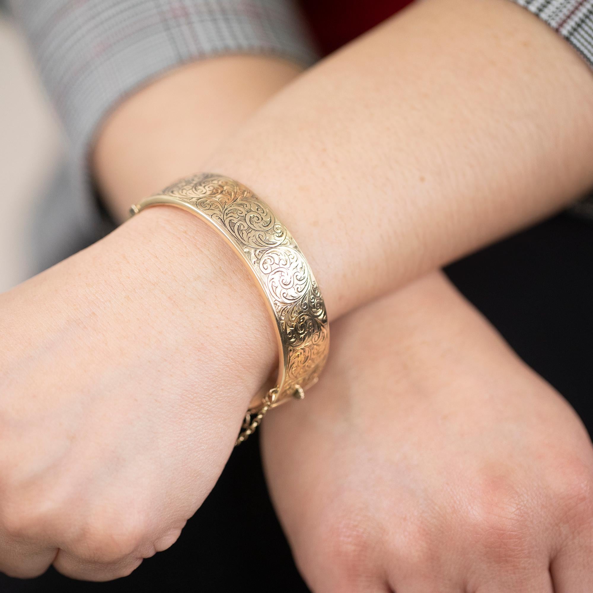 Wide hinged bangle with safety chain, featuring a meticulously hand-engraved scroll top. Hallmarked Birmingham 1946.

Metal: 9k yellow gold
Weight: 19.00 grams
Measurements: Inside diameter 5.7cm, Width 1.6cm
Era: Mid-Century Circa 1946