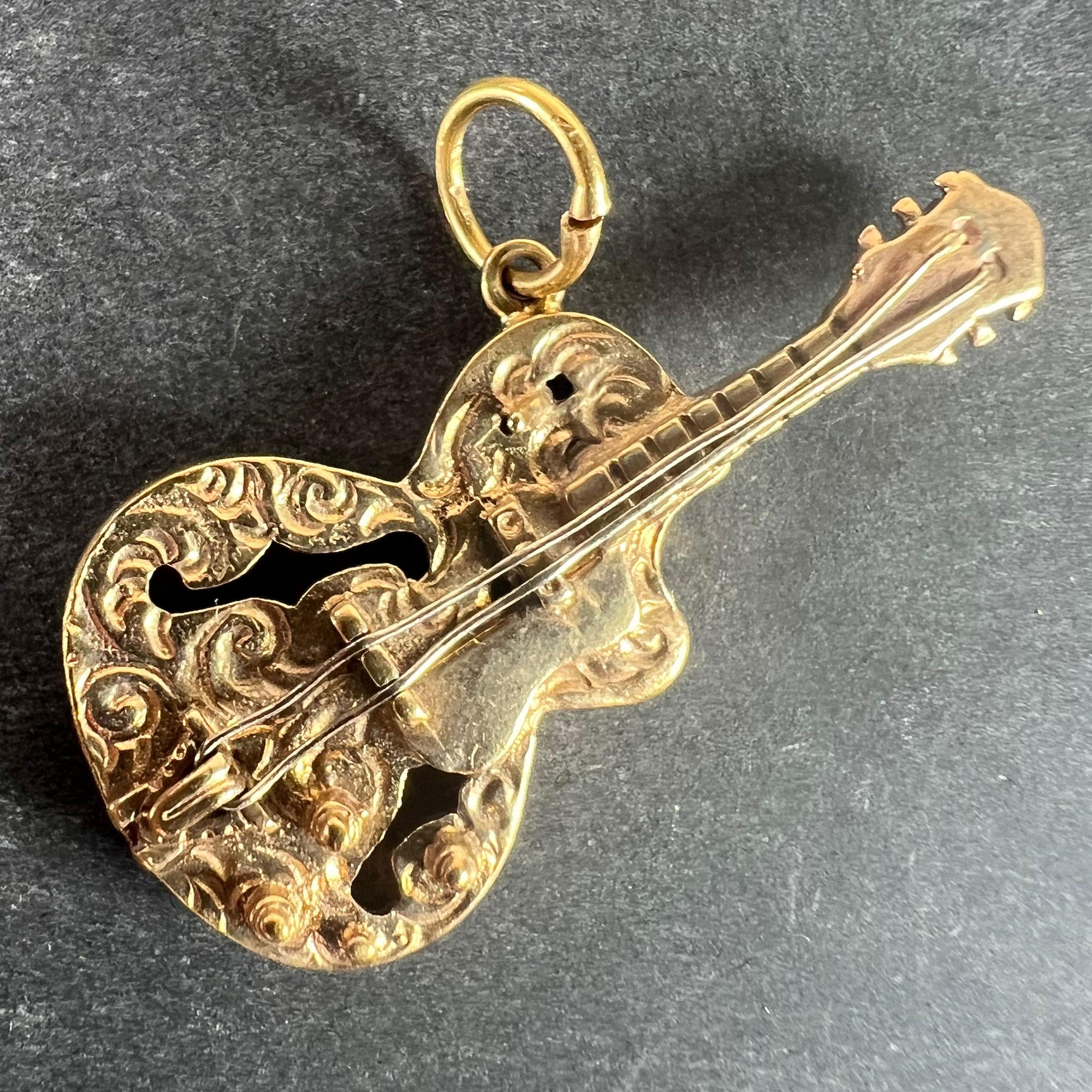 A  Pendentif charme vintage en or jaune 9 carats (9K) conçu comme une guitare électrique avec des cordes en or blanc. Poinçonné pour de l'or 9 carats, 1965 avec la marque du fabricant FM.

Dimensions : 3,7 x 1,8 x 0,6 cm (sans l'anneau de saut) :