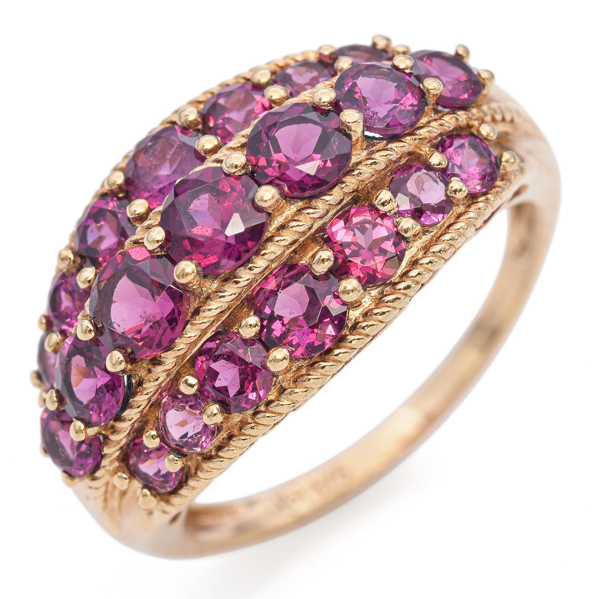 A vibrant display of color and craftsmanship. This striking ring showcases a series of round-cut garnets, each exuding a rich purple hue. The stones are meticulously set in three rows, creating a captivating visual effect. The garnets are securely