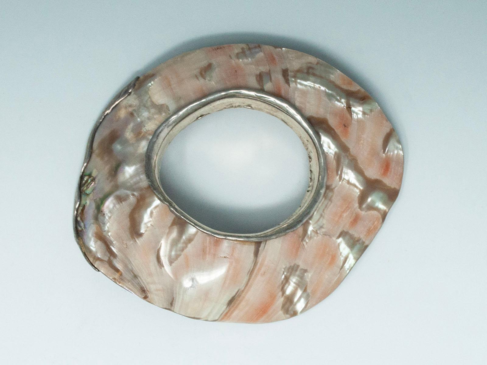 Vintage Abalone and Silver Artisan Bracelet

An incredible, large bracelet created from an abalone shell and mounted with silver at the wrist ( .5 inches wide) and along 4 inches of the outer edge. The shell is thick and sturdy with a smooth