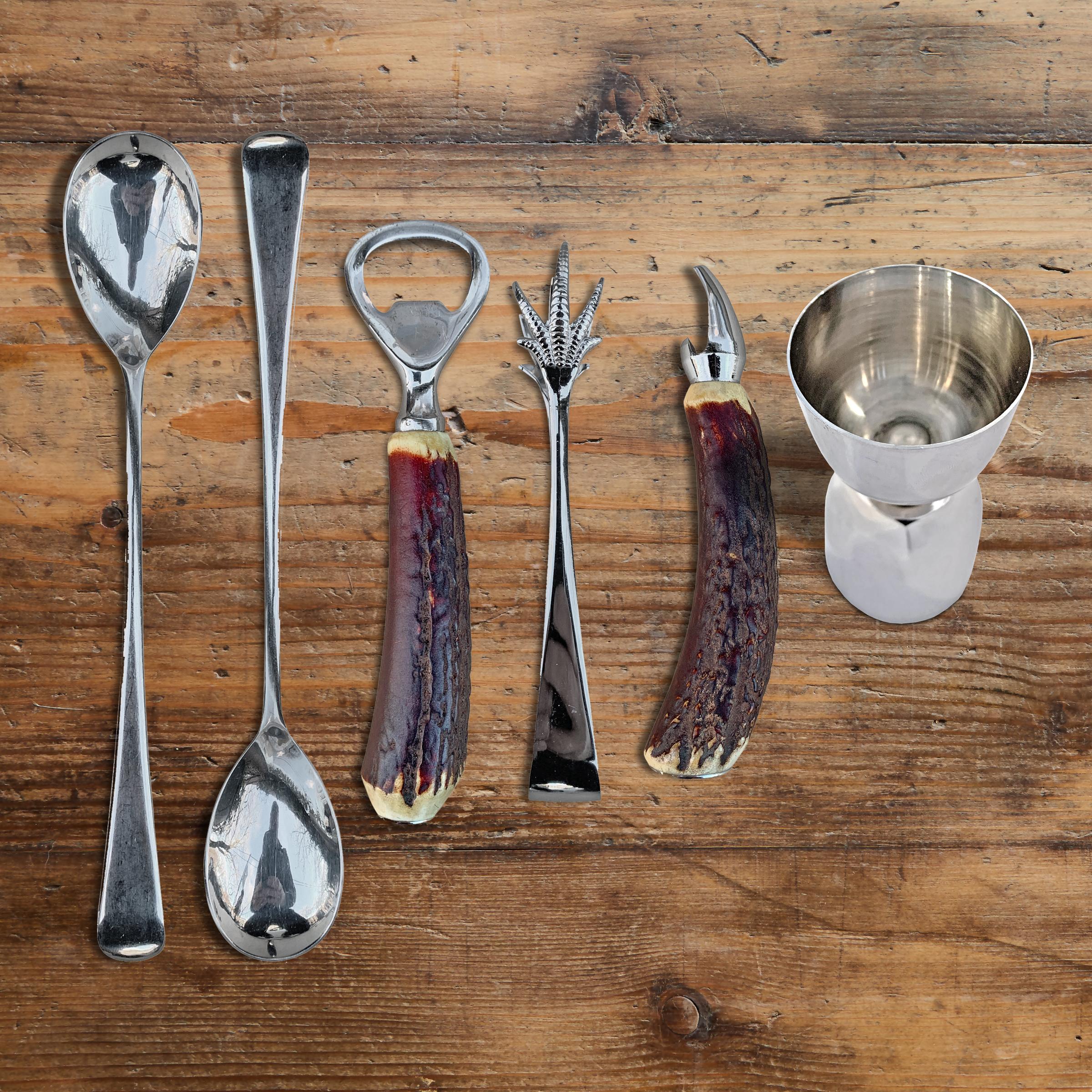 A wonderful set of vintage English bar tools made for Abercrombie and Fitch, with two stag horn handled bottle openers, two stir spoons, a pair of olive tongs, and a jigger with a 1 ounce and 1.5 ounce measure. Dimensions listed are for the spoon,