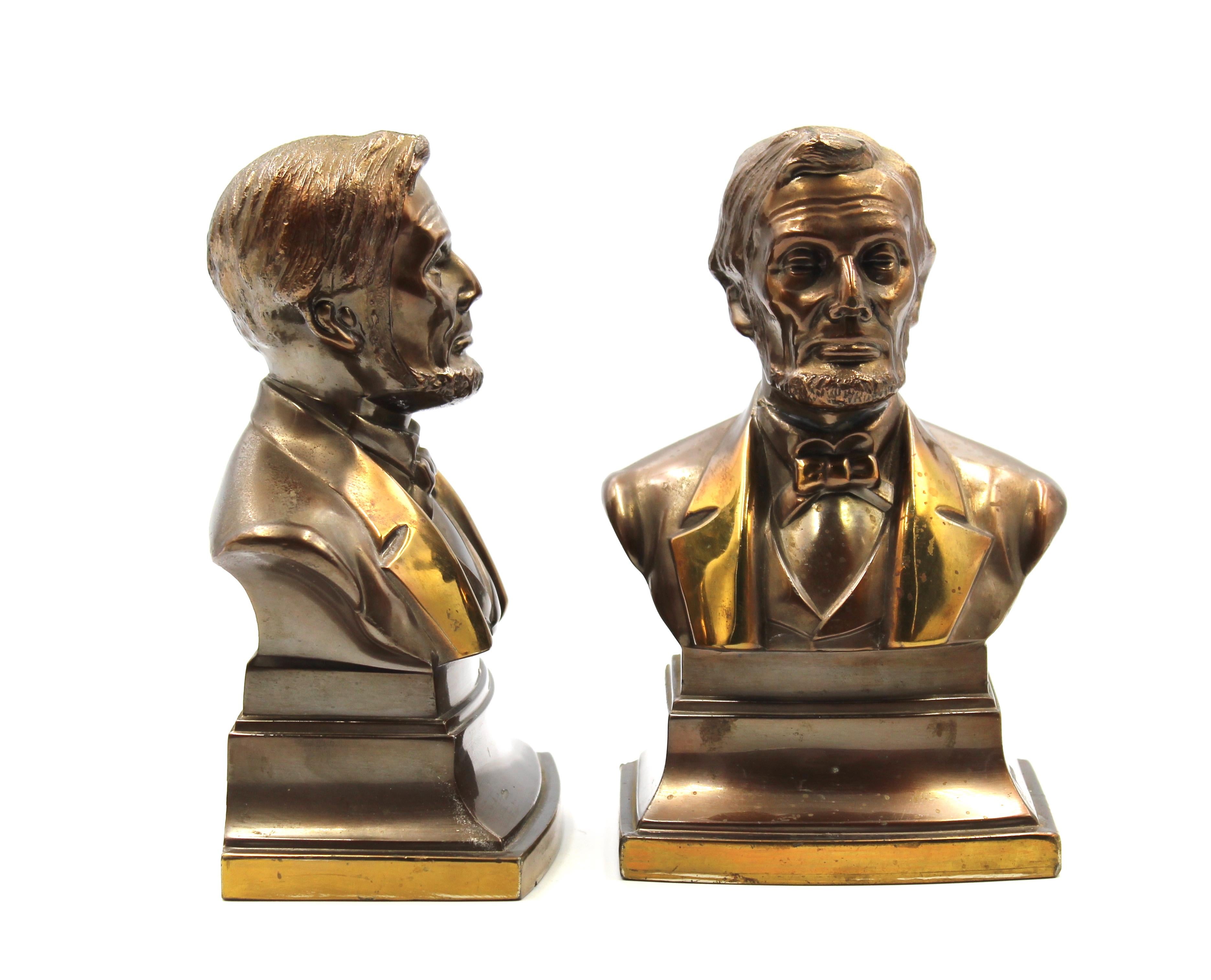 This is a pair of vintage Abraham Lincoln bust bookends. These bookends are made of brass and were produced by PM Craftsman in the United States. The bookends depict President Abraham Lincoln, from head to shoulders, atop small square pedestals.