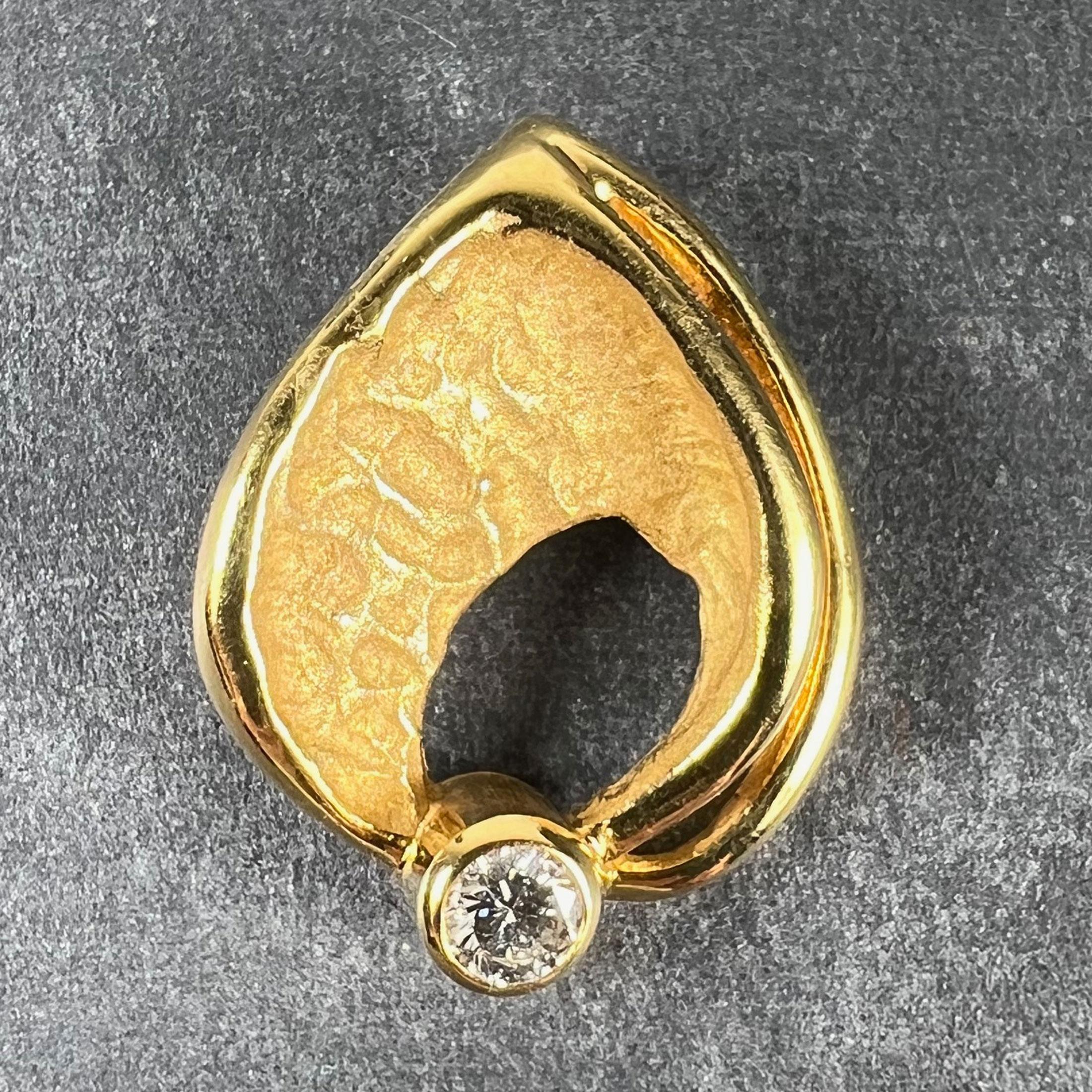 Colgante vintage de oro amarillo de 18 quilates (18K) diseñado como una hoja abstracta, engastado en las bases con un diamante redondo talla brillante de aproximadamente 0,15 quilates, estimado como color F-G y claridad VS (la piedra no se ha sacado