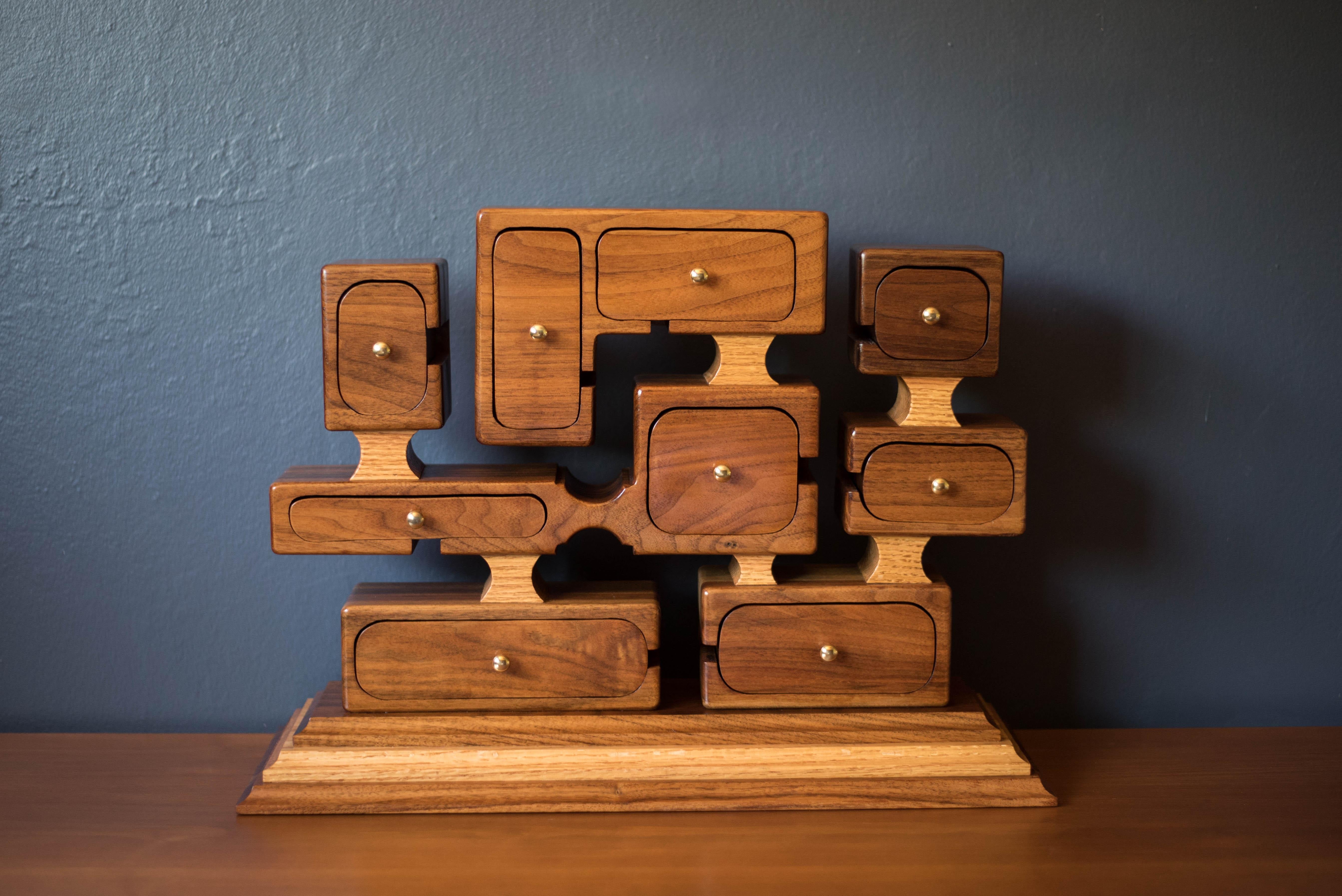 Mid-Century Modern studio organizing jewelry box circa 1970's. This unique piece is handcrafted in solid walnut and oak. Equipped with nine sculptural compartment boxes in various shapes and sizes accented with brass pulls and includes interior felt