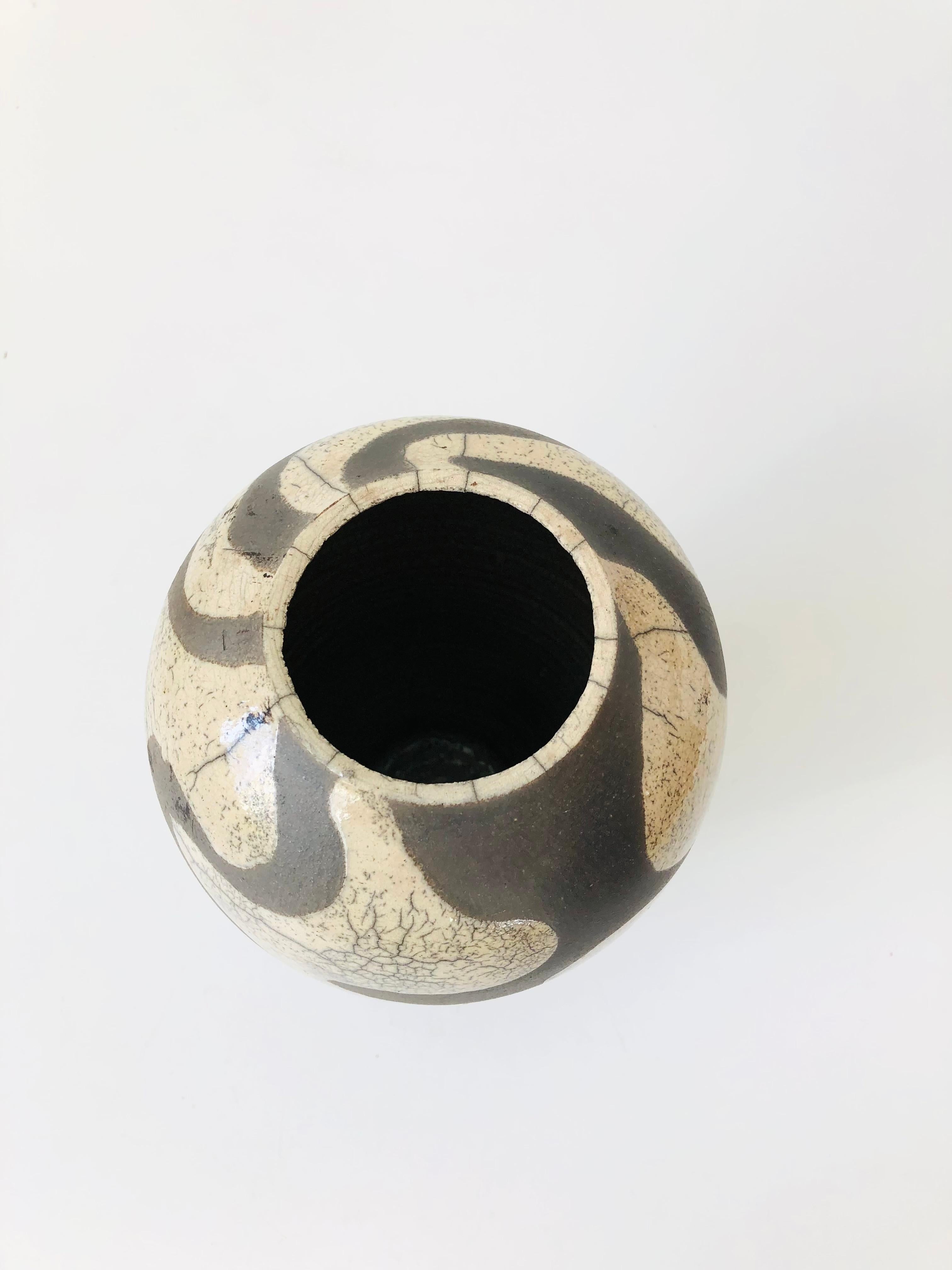 A wonderful vintage raku pottery vase. Two toned glazes in a unique abstract pattern of contrasting off-white crackle glaze over a matte dark charcoal. Signed on the base. A beautiful piece in a versatile medium size.

