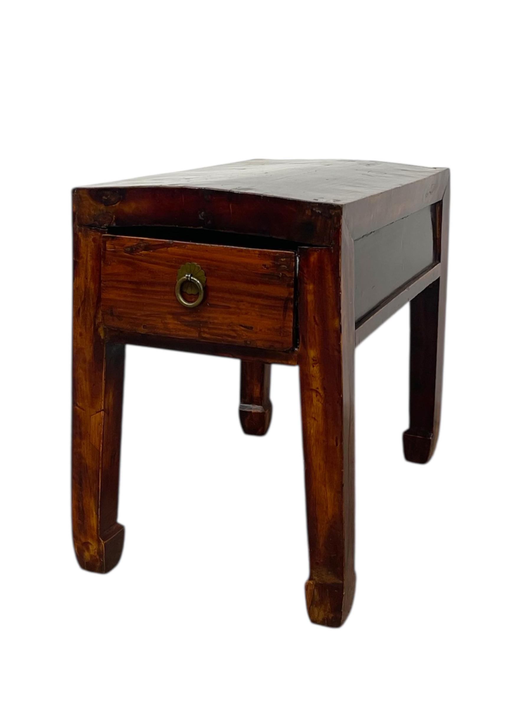  This vintage accent table is crafted in the style of traditional Chinese furniture, featuring a warm distressed elm wood finish that highlights its natural grain and age. The table stands on squared legs that curve gently at the feet, a detail