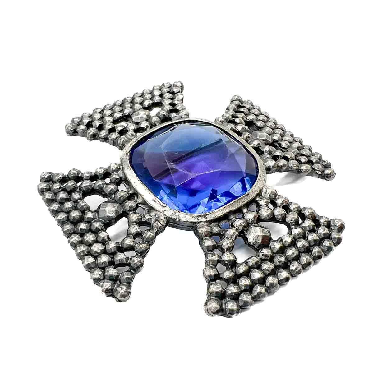 A striking Vintage Accessocraft NYC Cruciform Brooch. An eternally stylish cruciform design adorned with a large stone of sapphire blue with an amethyst flash across the centre, sometimes referred to as a rainbow stone. The setting of the brooch