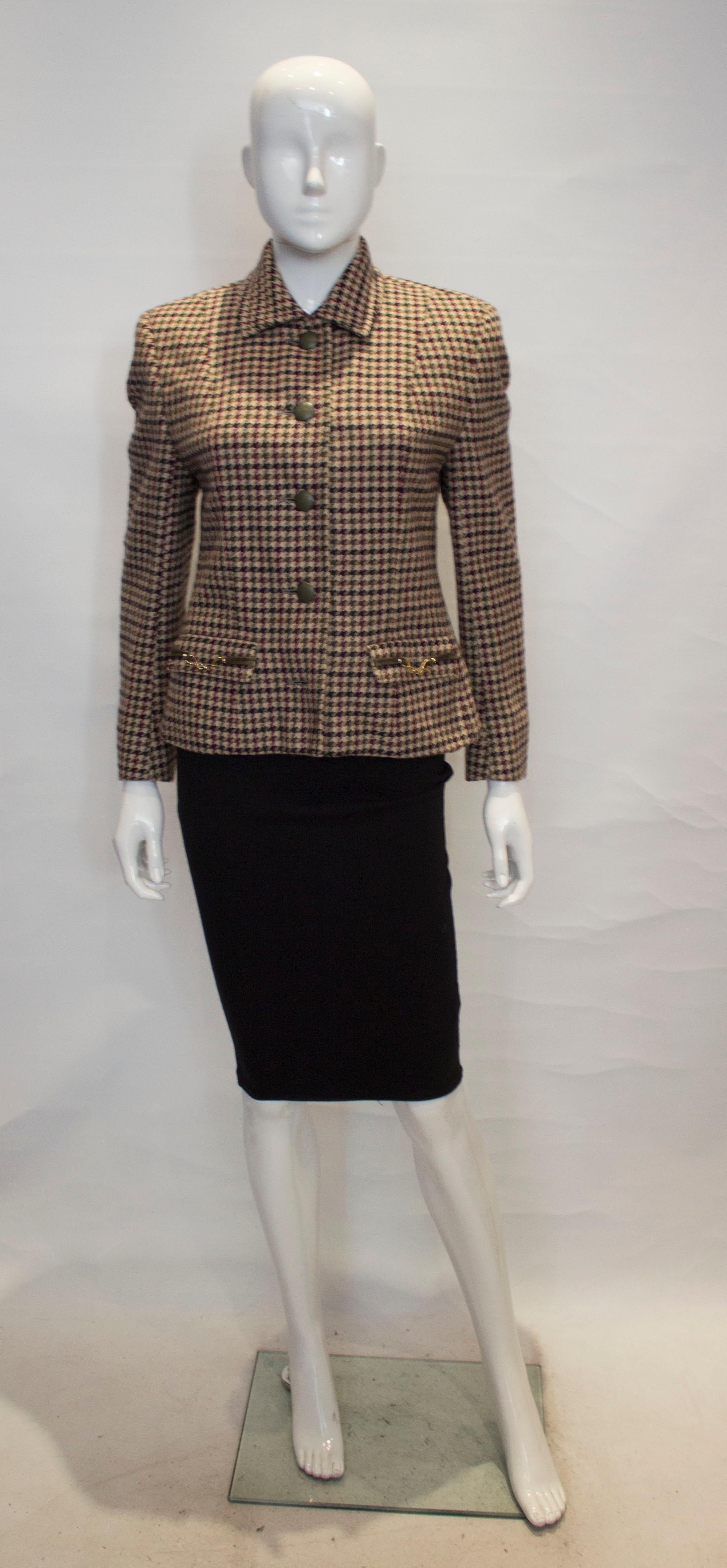 A vintage winter jacket by Acquascutum. The jacket is in an ivory , green, burgudny and black mix with sage green buttons.  It has a central five button opening and two buttons on each cuff,  and a flap pocket on either side at hip leval.