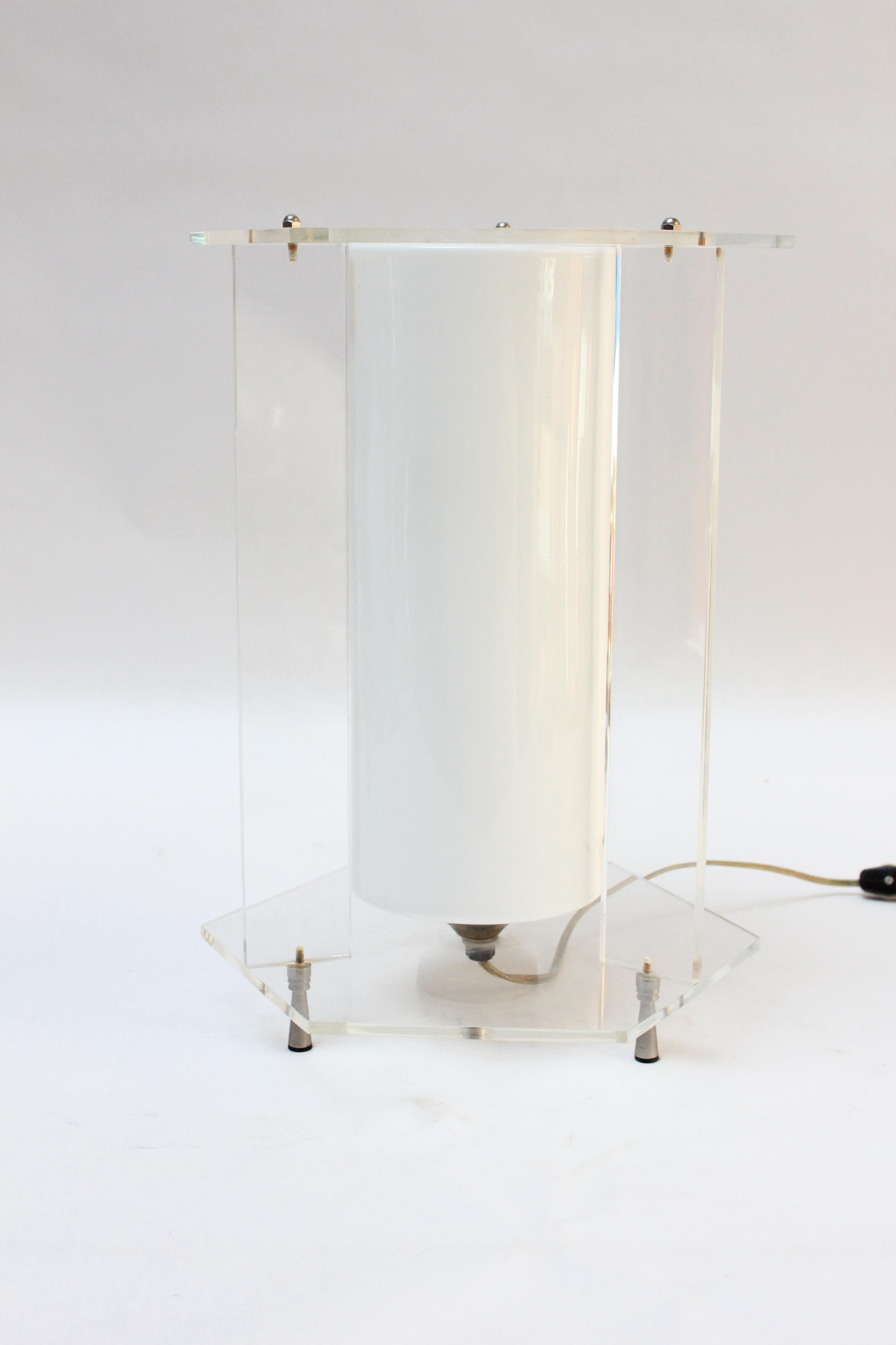 Acrylic hexagonal-form table lamp with a white cased-glass inset cylinder, all supported by three conical metal feet (ca. USA, 1970s).
Very fine, vintage condition with only light scuffs to the bottom acrylic tier and metal components.
Height: 15.25