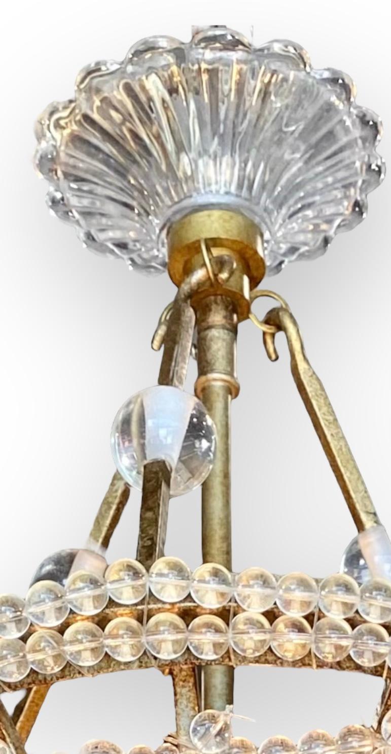 Charmant lustre suspendu en acrylique à trois lumières, avec disques de fleurs et perles câblées. Une belle couronne couronne ce luminaire et le métal est fini pour s'harmoniser avec l'argent ou l'or. 