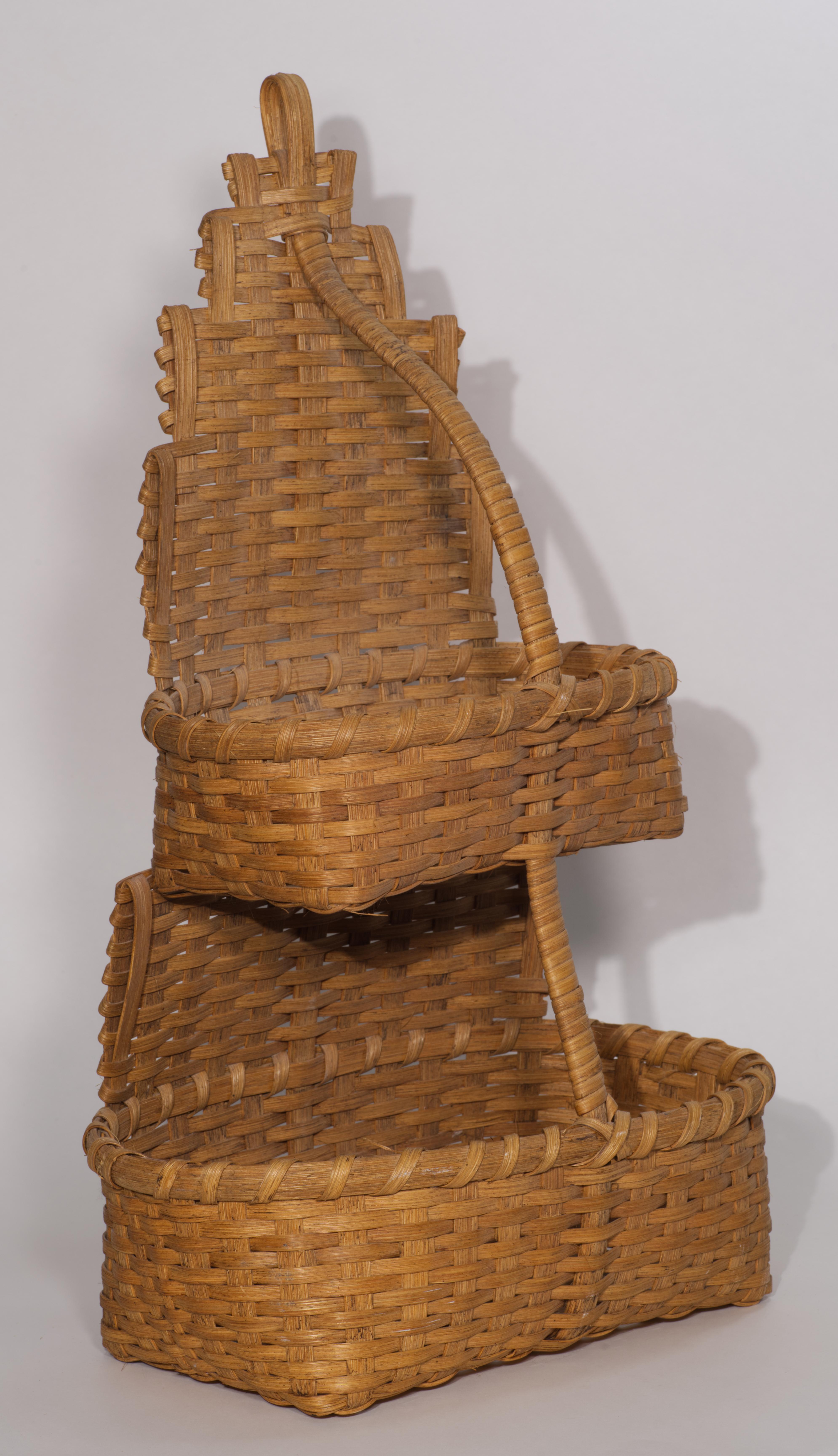 Il cesto tradizionale vintage a più livelli è composto da due cesti collegati da un pannello piatto intrecciato; i supporti strutturali e la maniglia rendono il cesto robusto e gli permettono di stare in piedi da solo. Questo tipo di cesto è